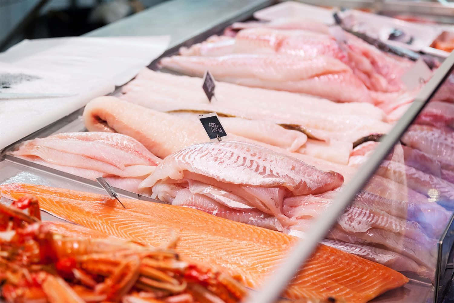 Seafood 桌布 壁紙 — 新鮮生魚片，包括三文魚和白魚，陳列在冷藏市場陳列櫃中，附有價格標籤。