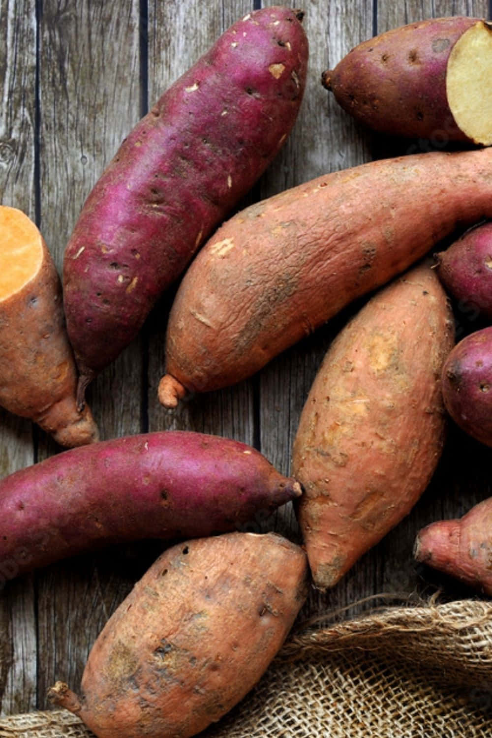 Red Potatoes 桌布 壁紙 — 新鮮的番薯以大地色調放置在風化的木材和麻布上，展現自然質感和鄉村魅力。
