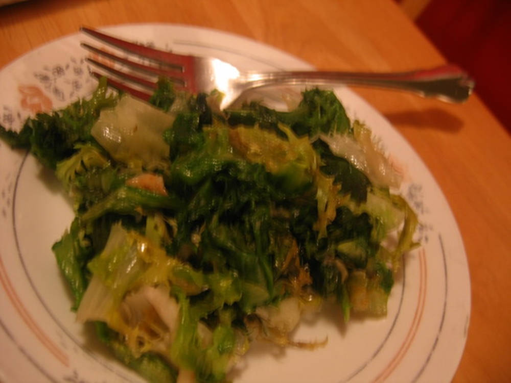 有圖案的碟子上盛著炒蔬菜和洋蔥，叉子放在木桌上。