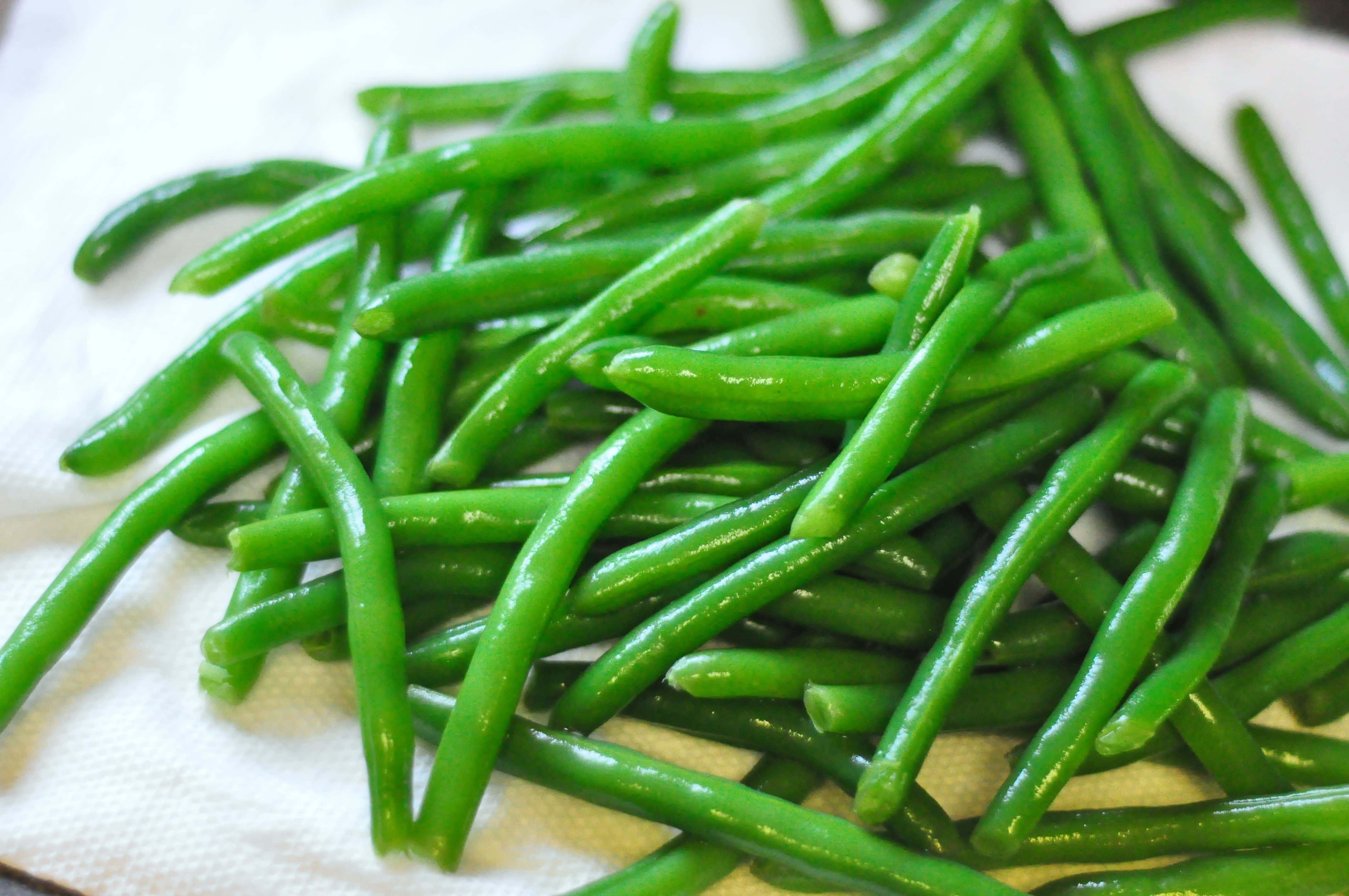 beans 桌布 壁紙 — 新鮮翠綠的四季豆閃爍著水珠，堆疊在白色紙巾上。