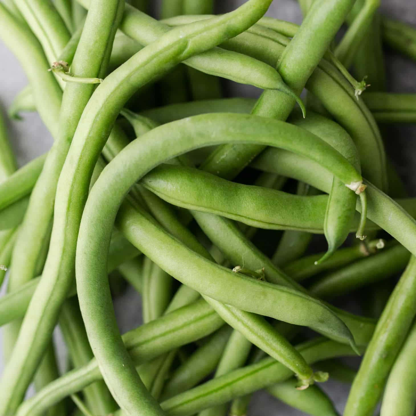 beans 桌布 壁紙 — 新鮮翠綠的豆角堆疊在一起的特寫，帶有自然紋理和柔和陰影。