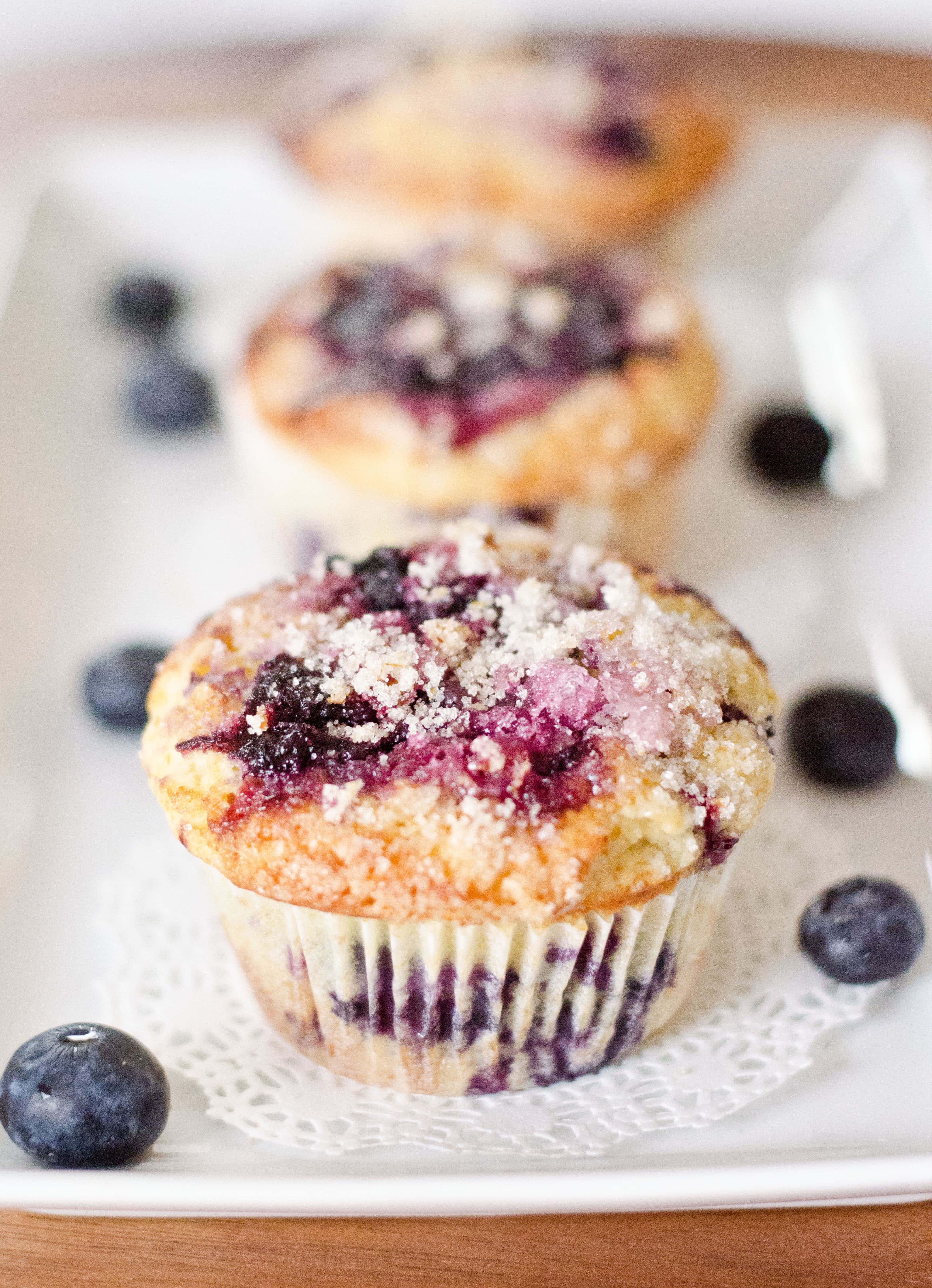 Blueberry Muffins 桌布 壁紙 — 新鮮藍莓鬆餅配酥粒頂層，放在白色碟上，周圍環繞著整顆莓果。