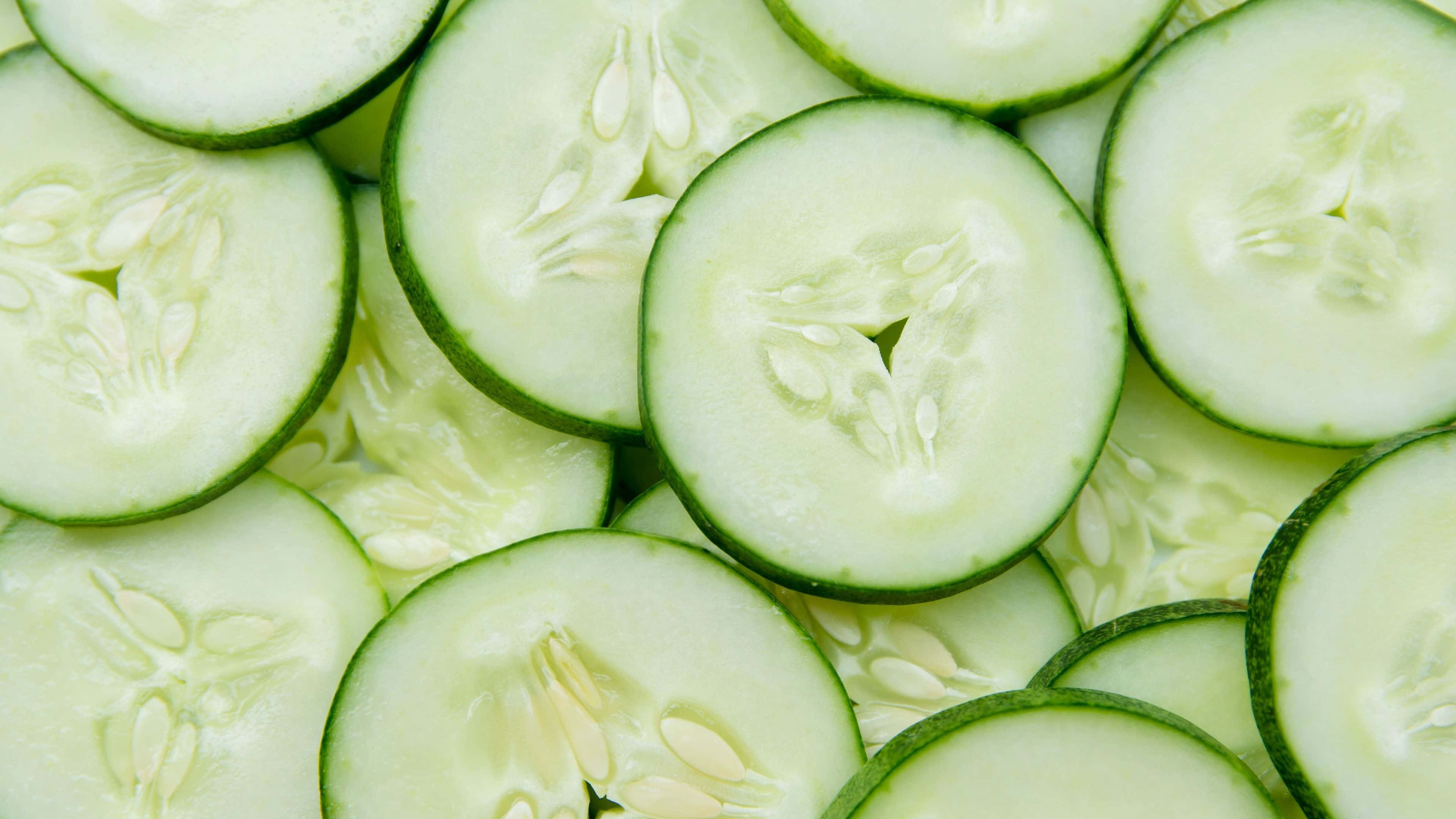 cucumber 桌布 壁紙 — 新鮮青瓜片排列成充滿活力的綠色圖案，展示其爽脆質地和淡色種子。