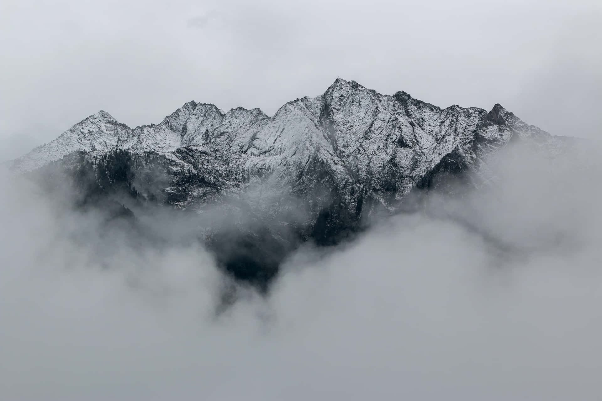 白雪覆蓋的山峰在灰暗的日子裡從濃密的雲層中浮現。
