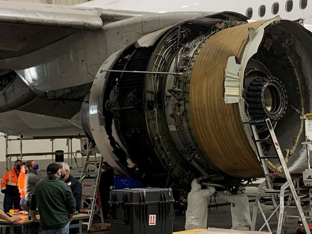 技術人員在飛機機庫中檢查大型噴射引擎。