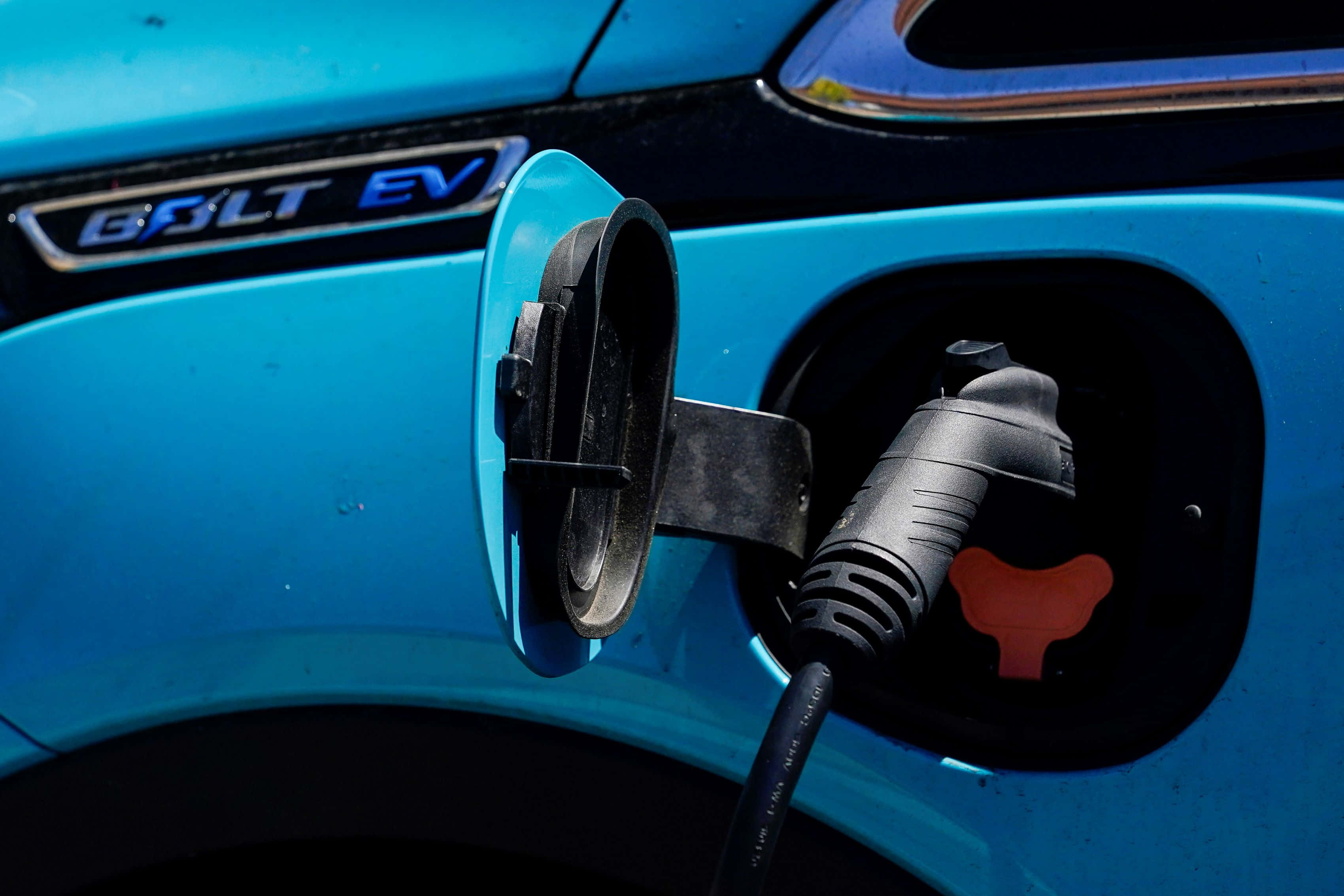 Electric Vehicle 桌布 壁紙 — 日光下插入黑色插頭的亮藍色GOLT EV充電埠特寫。