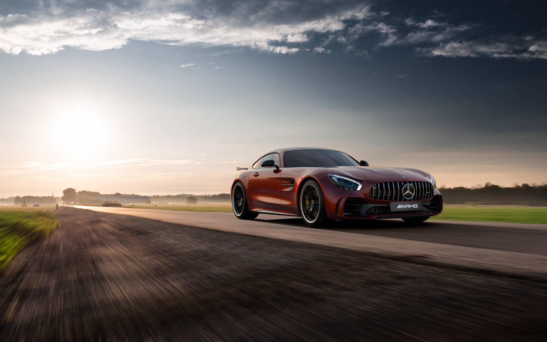 紅色 Mercedes-AMG GT 在日落時分在鄉村道路上疾馳。