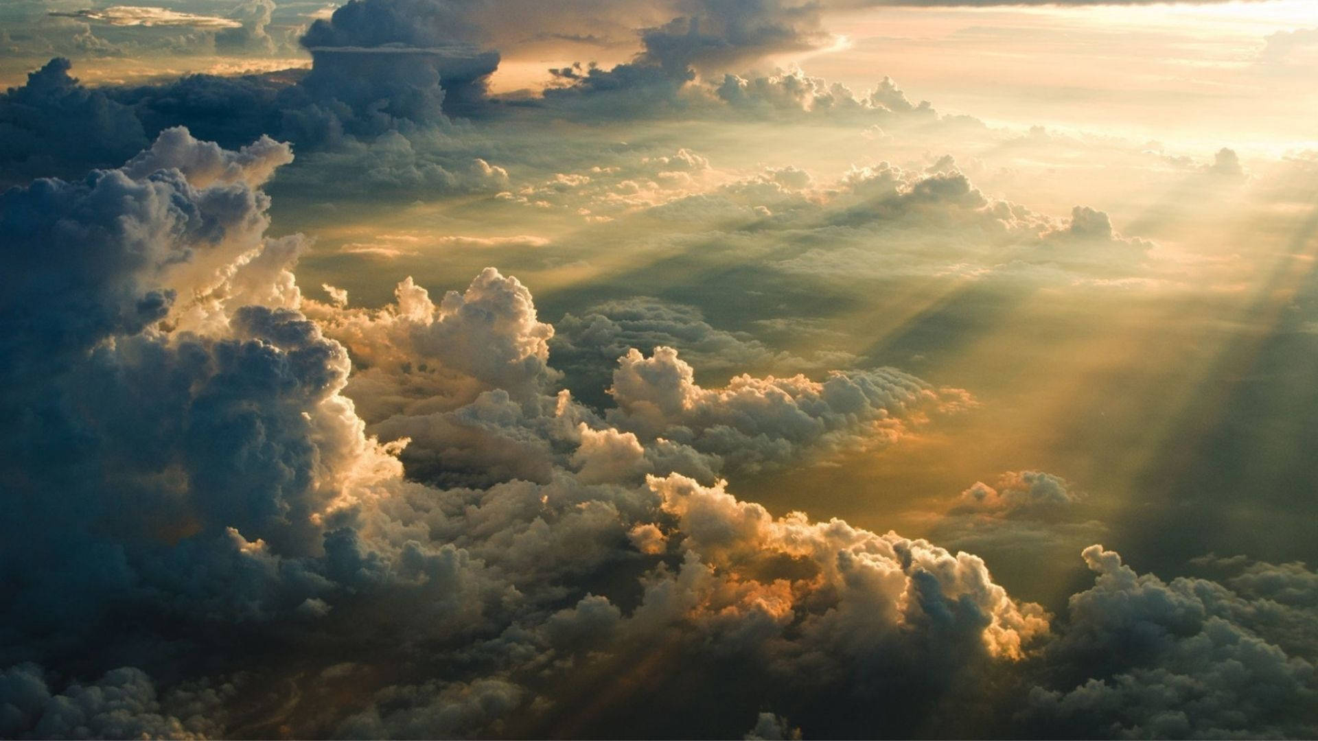 日出天際 壁紙 — 金色陽光穿透戲劇性的雲層，在日出或日落時呈現令人驚嘆的空中景觀。