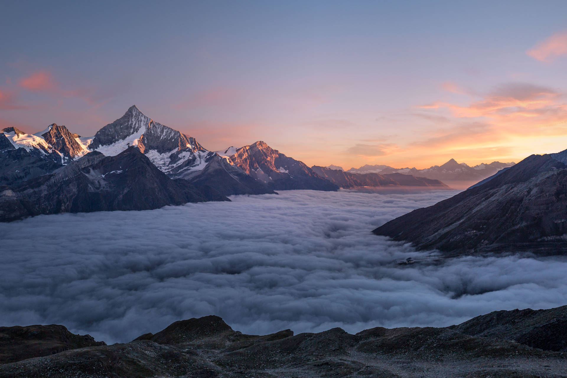 積雪的山峰在日出時聳立於雲海之上。