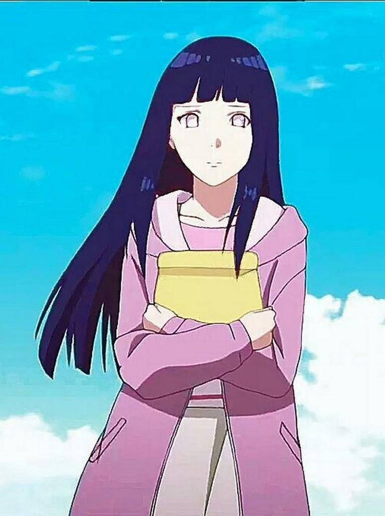 日向雛田——光耀的堅強與決心 壁紙 — 長黑髮的動漫女孩穿著粉紅色連帽衫，拿著一本黃色書，背景是明亮的藍天和蓬鬆的雲朵。