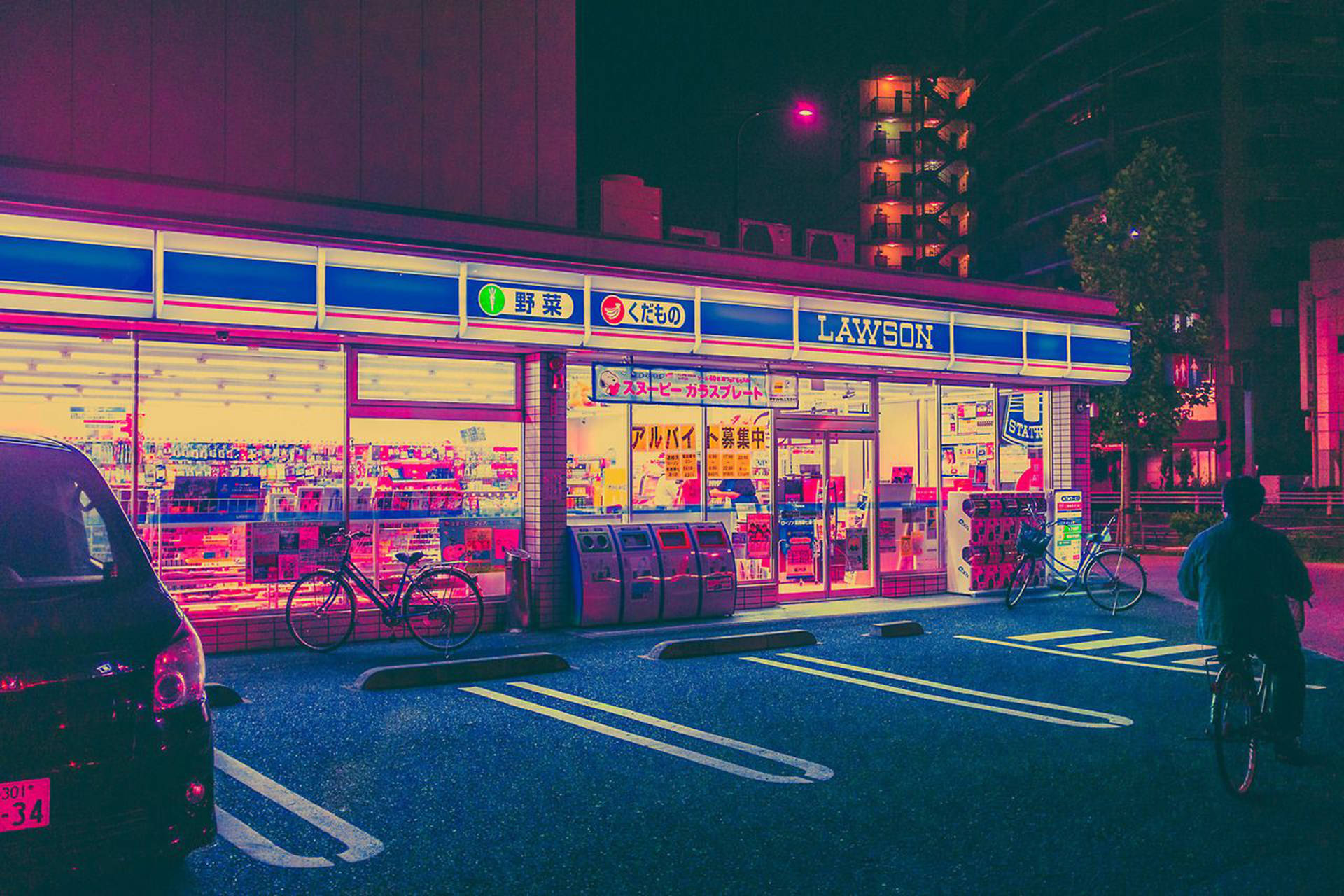 一名單車手在夜晚騎過一間燈火通明的Lawson商店，有霓虹招牌和泊車。