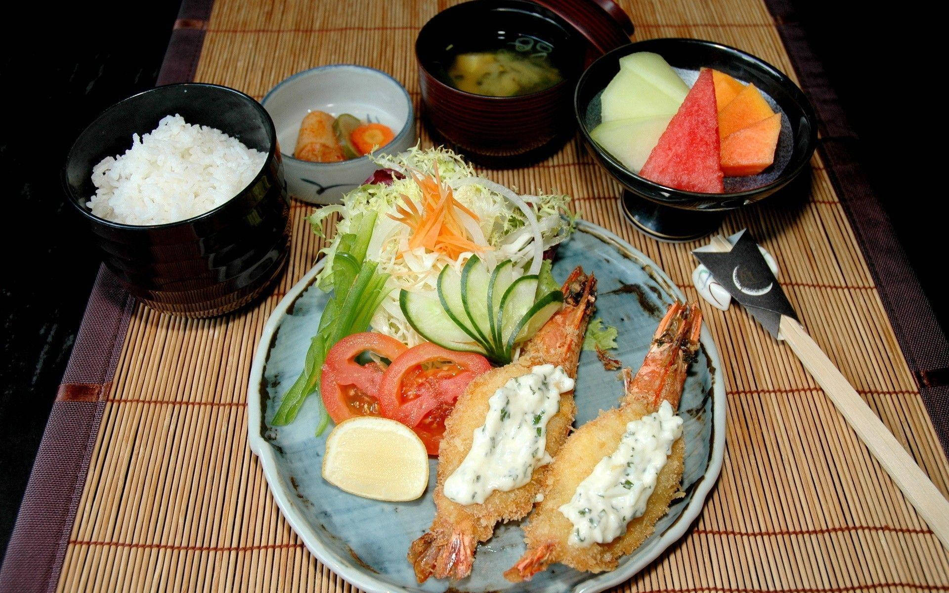 日式美味午餐：酥脆天婦羅與新鮮蔬菜 壁紙 — 一個精美擺盤的日式餐點，包括天婦羅蝦、沙律、米飯、味噌湯和水果，放在竹蓆上。