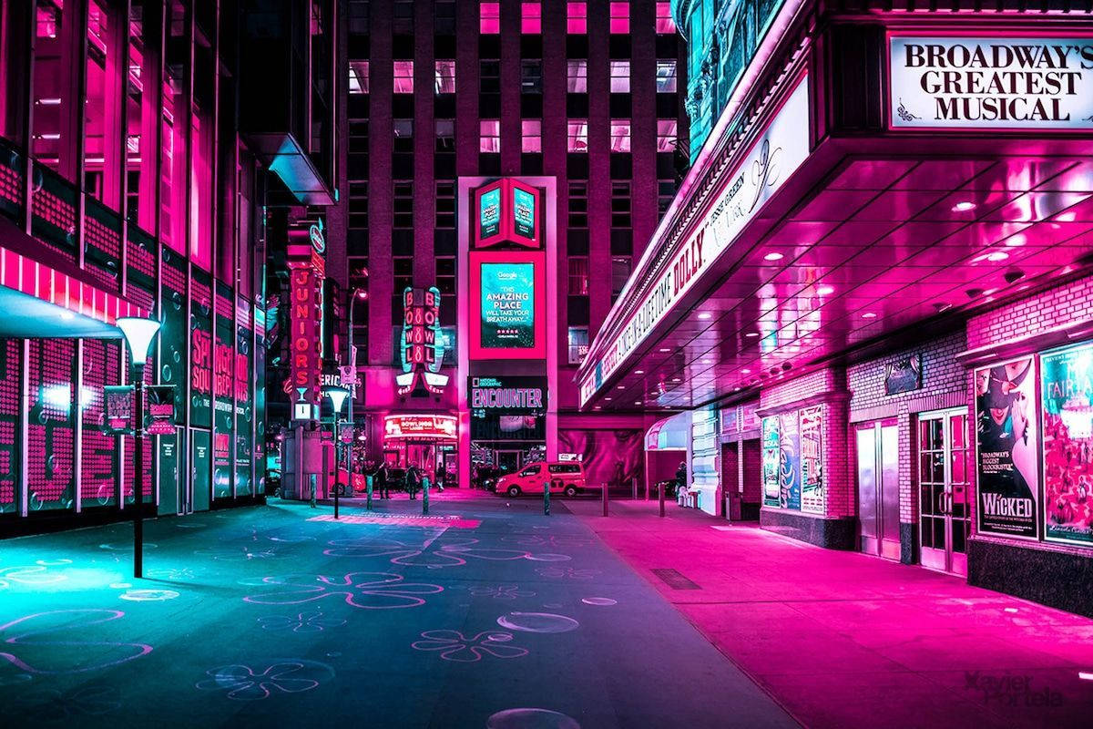 夜晚霓虹燈照亮百老匯劇院街，人行道上有發光的藝術圖案。