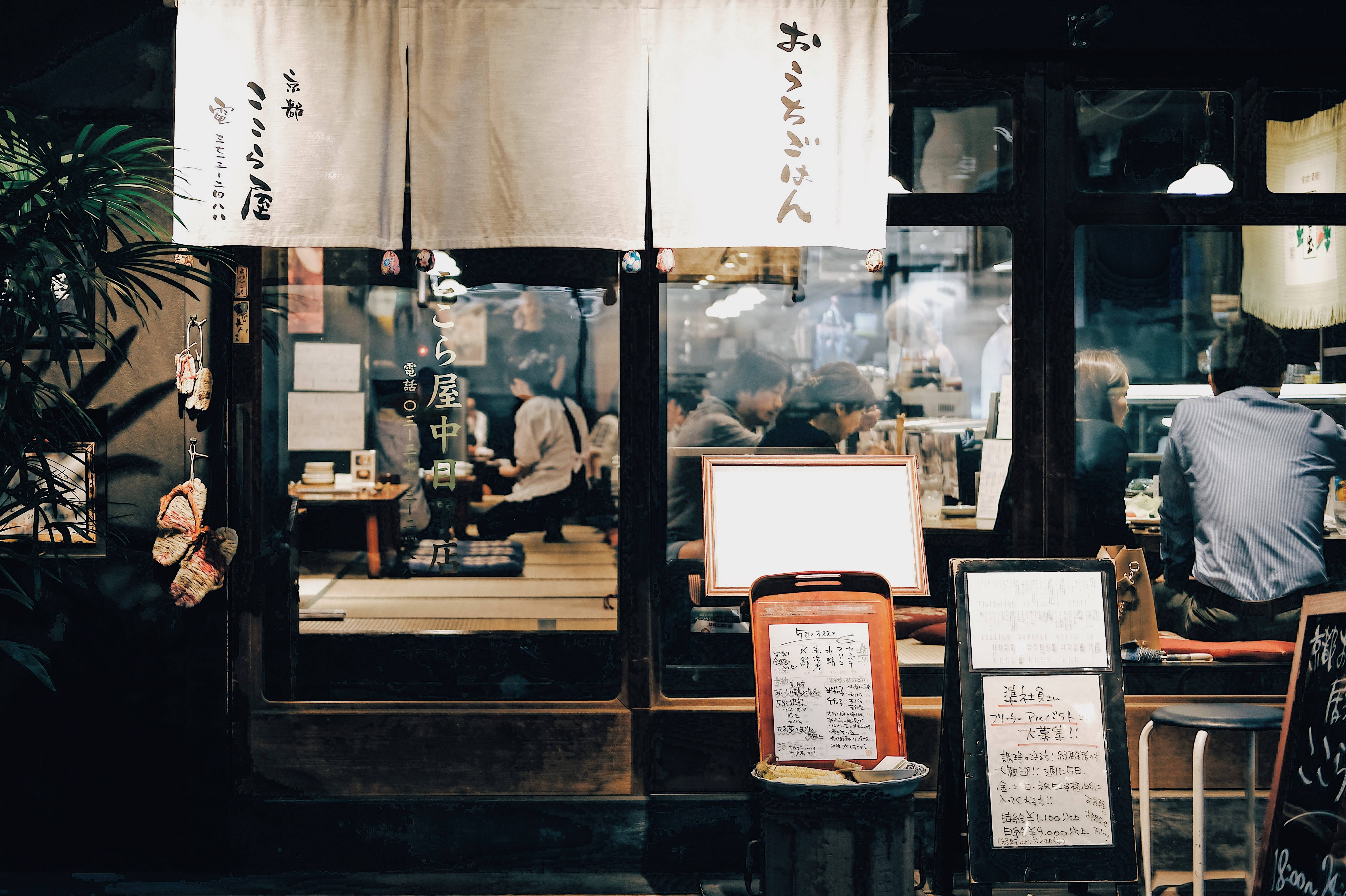 日式高畫質餐廳招牌與橫幅 壁紙 — 夜晚一間舒適的日本餐廳，室內燈光溫暖，有顧客在內用餐。