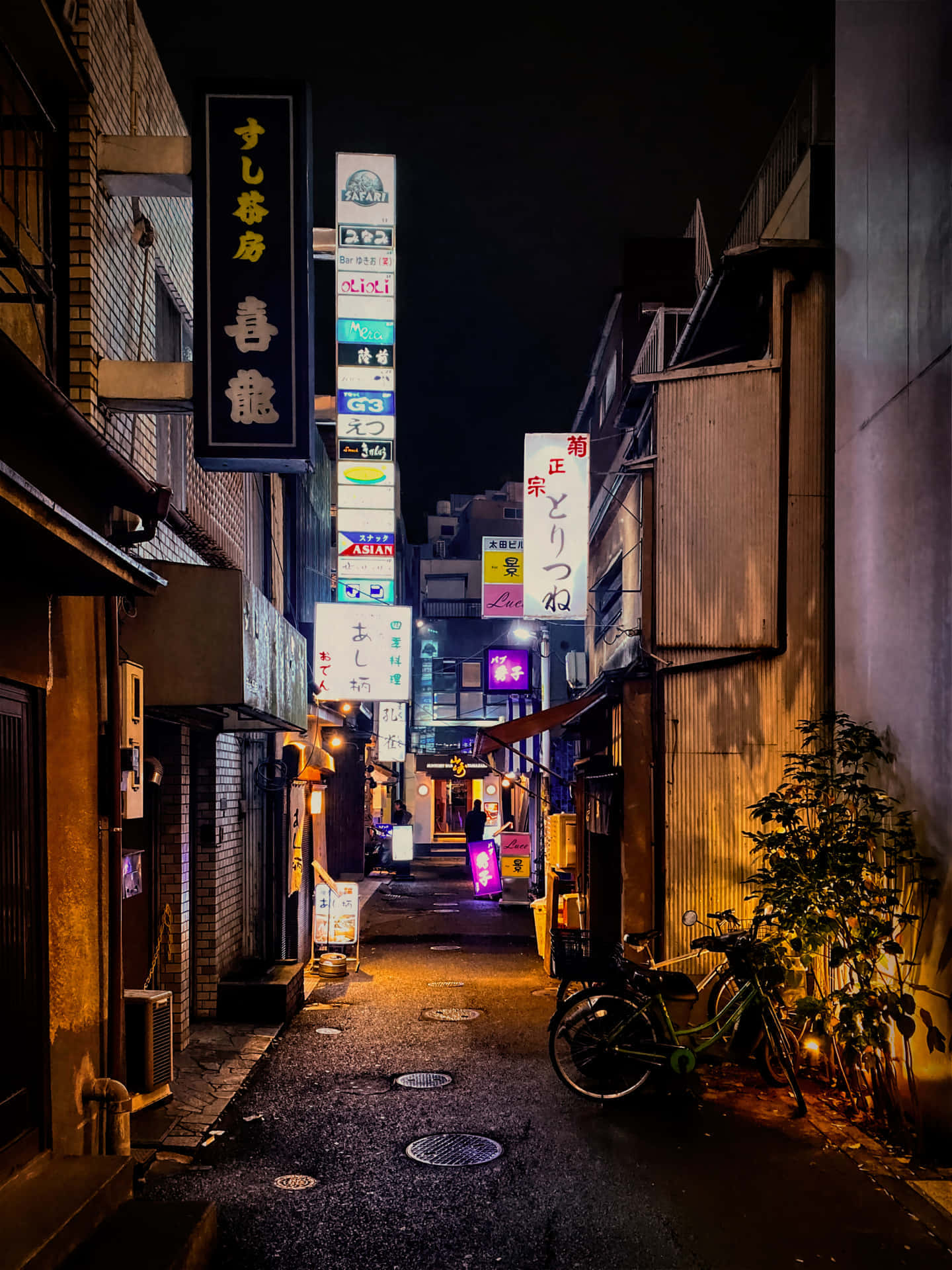 日文招牌巷弄背景 壁紙 — 夜晚東京一條狹窄小巷，被發光的霓虹燈招牌和溫暖的路燈照亮，投下長長的影子。