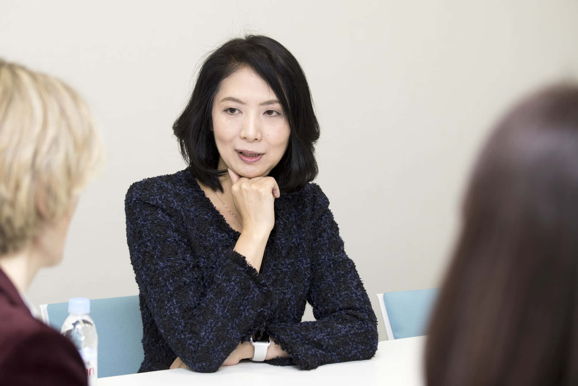 一位女性在會議室與同事在桌子旁交談。