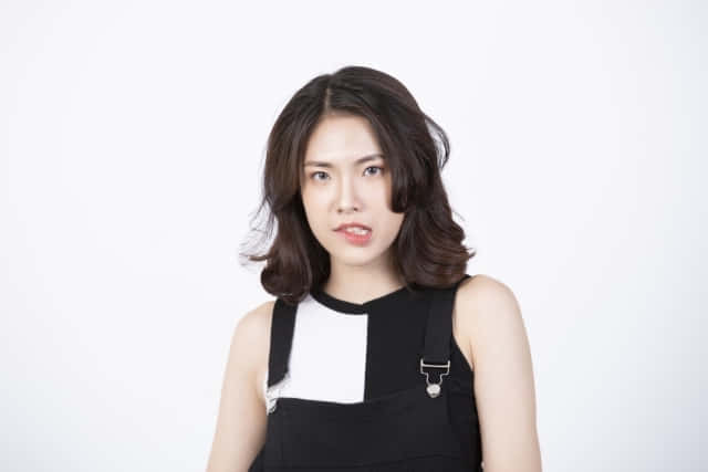 穿著黑白上衣的年輕女性在攝影棚直視鏡頭
