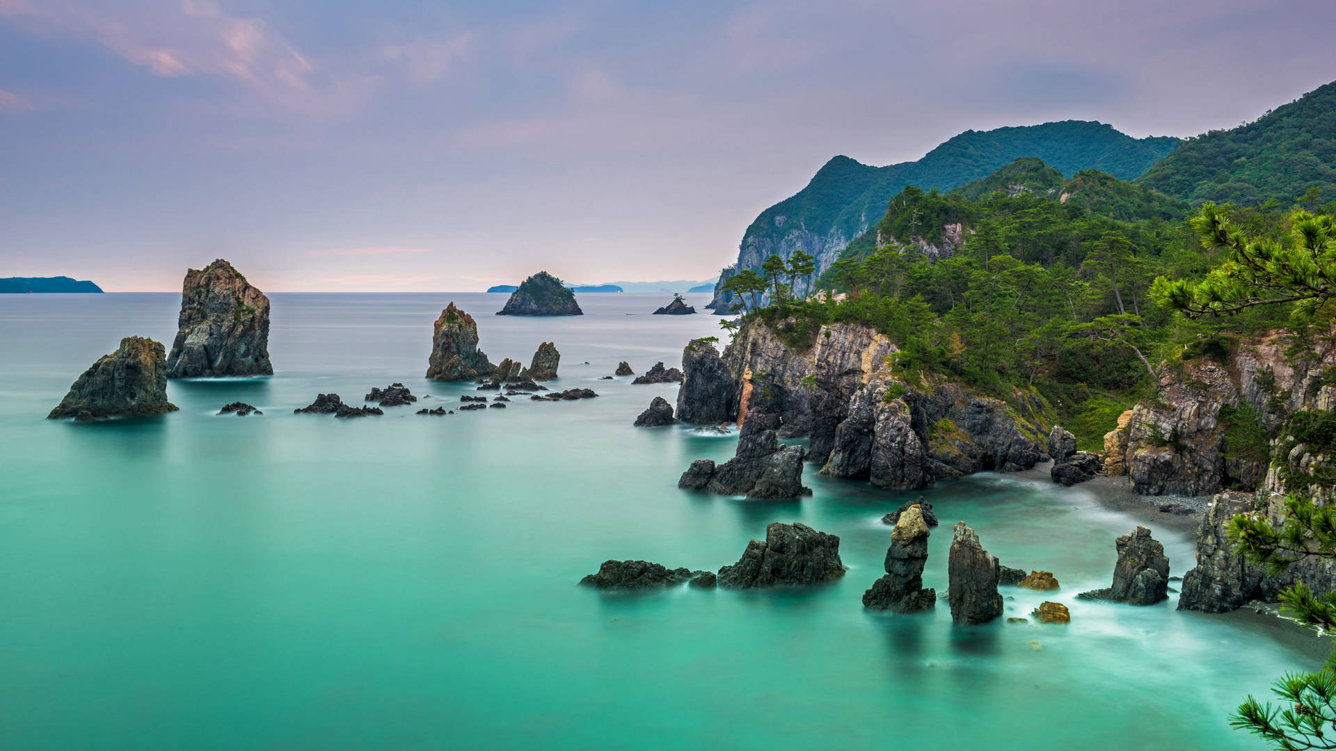 暮色中的海岸景色，碧綠色的海水和岩石峭壁。