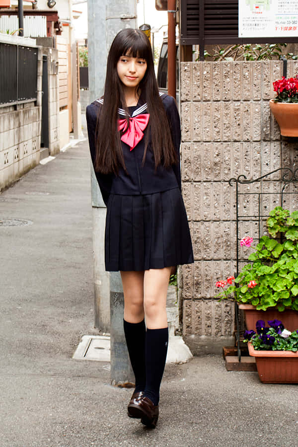 穿著日本校服的少女，站在狹窄小巷中，旁邊有盆栽植物。