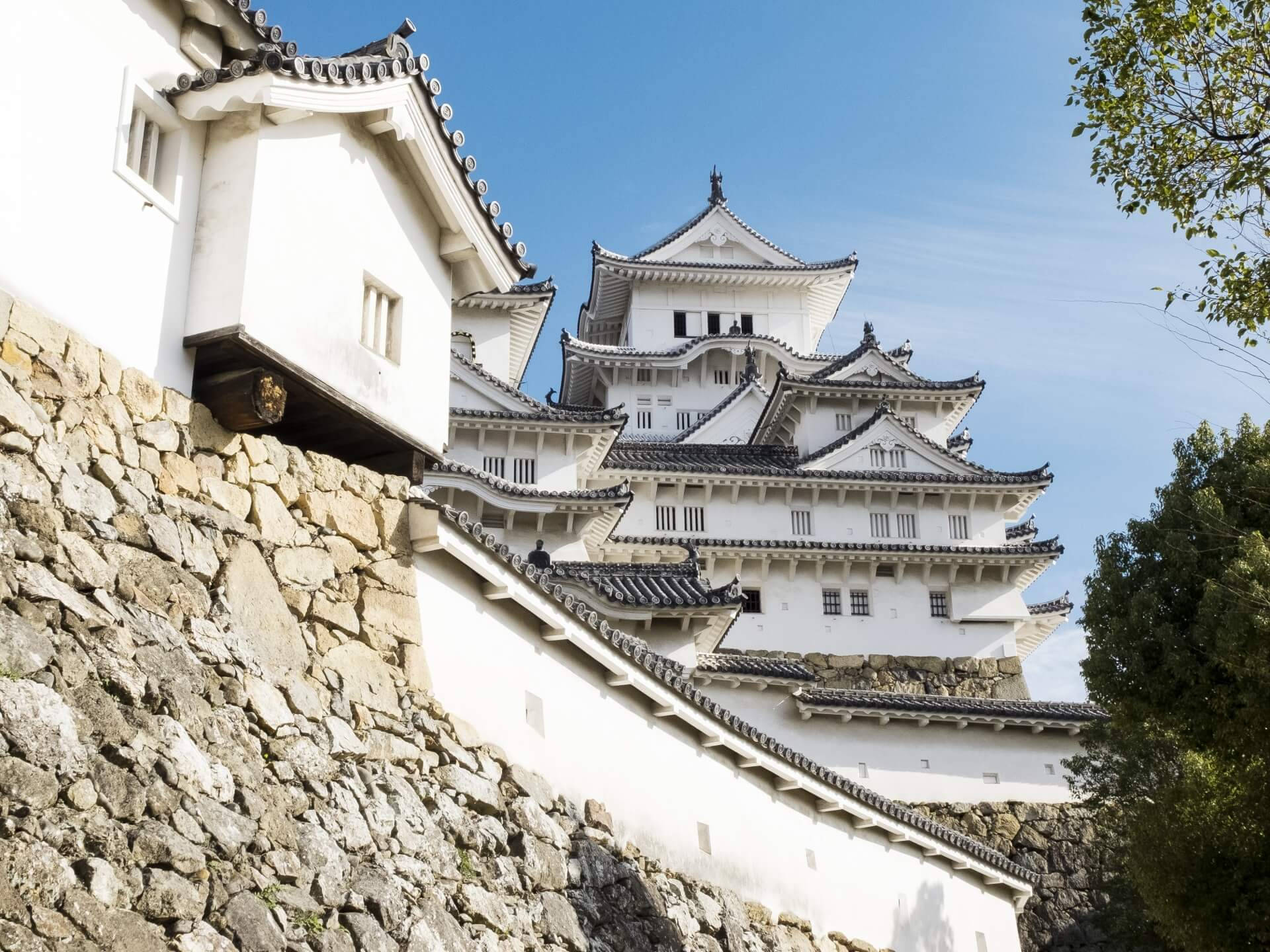 晴朗藍天下，擁有石牆和分層屋頂的白色日本城堡。