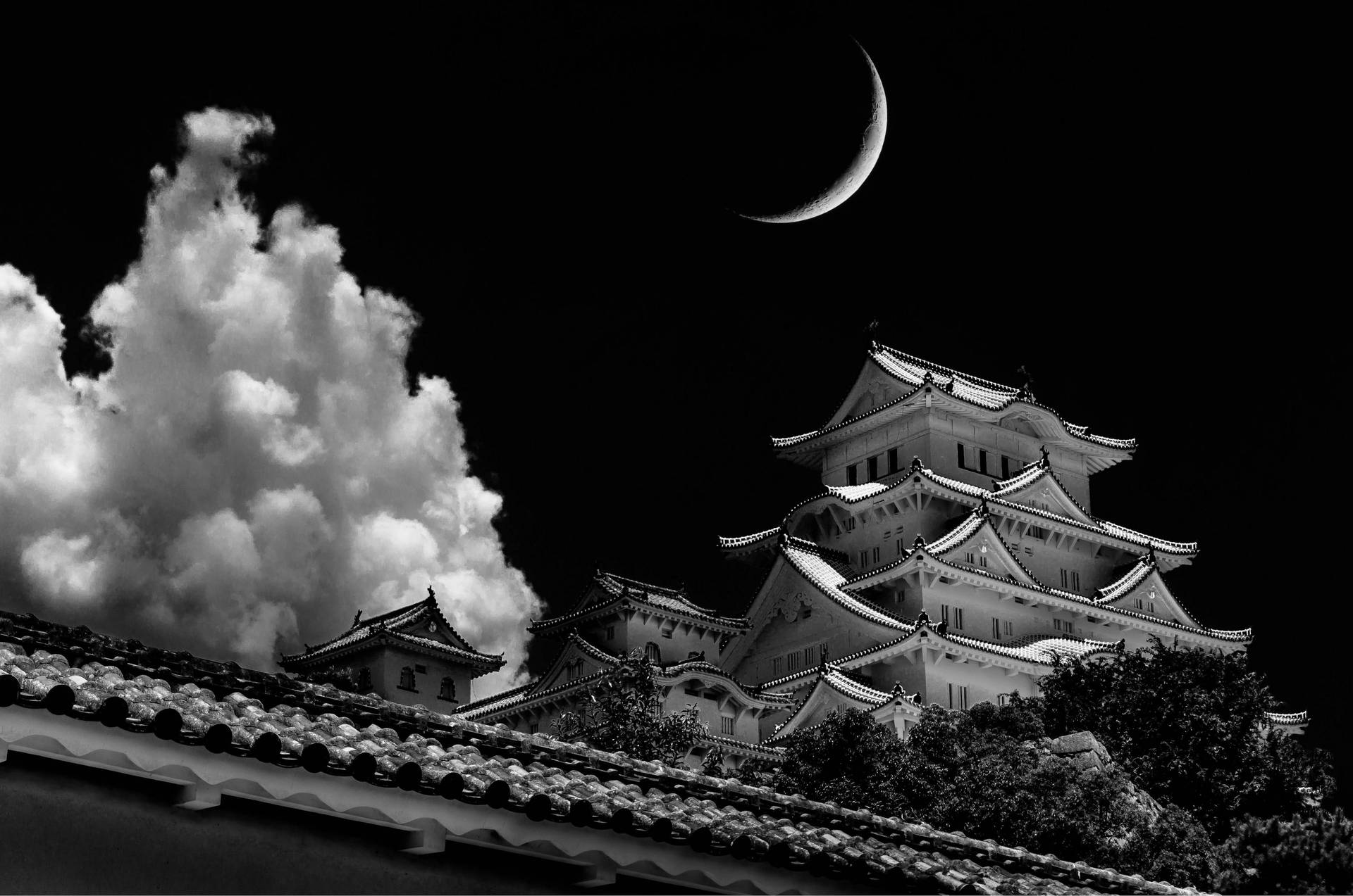 夜晚彎月與戲劇性雲層下的日本城堡。