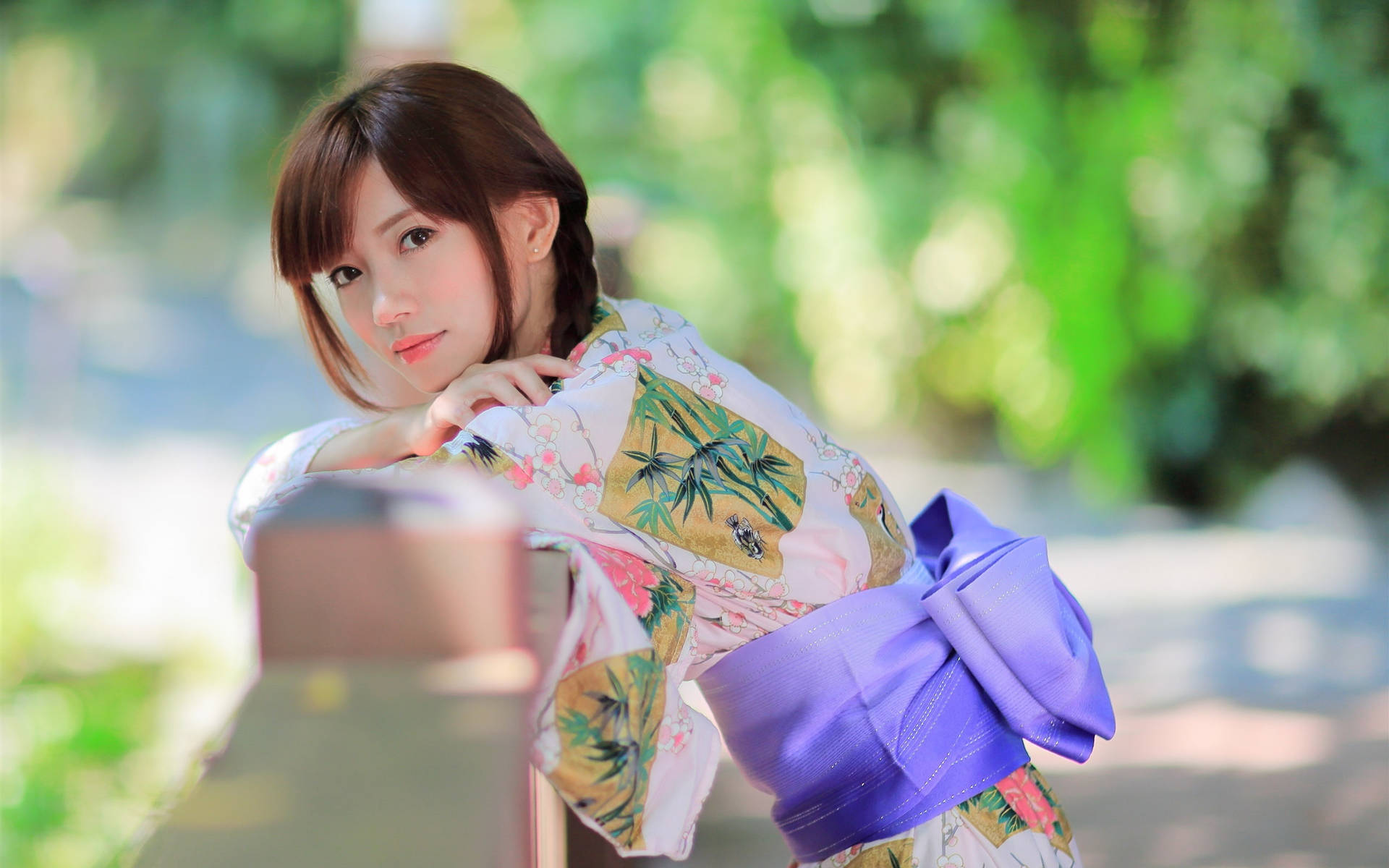 年輕女子穿著花卉和服靠在花園木欄杆上