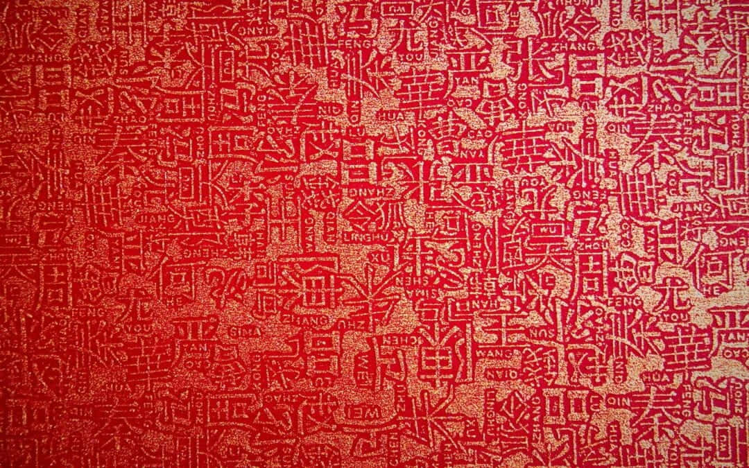 日本文化在紅色中甦醒，展現生命與成長之美 壁紙 — 一張充滿活力的紅色紋理牆紙，上面密密麻麻地覆蓋著各種字體和大小的金色中文字。
