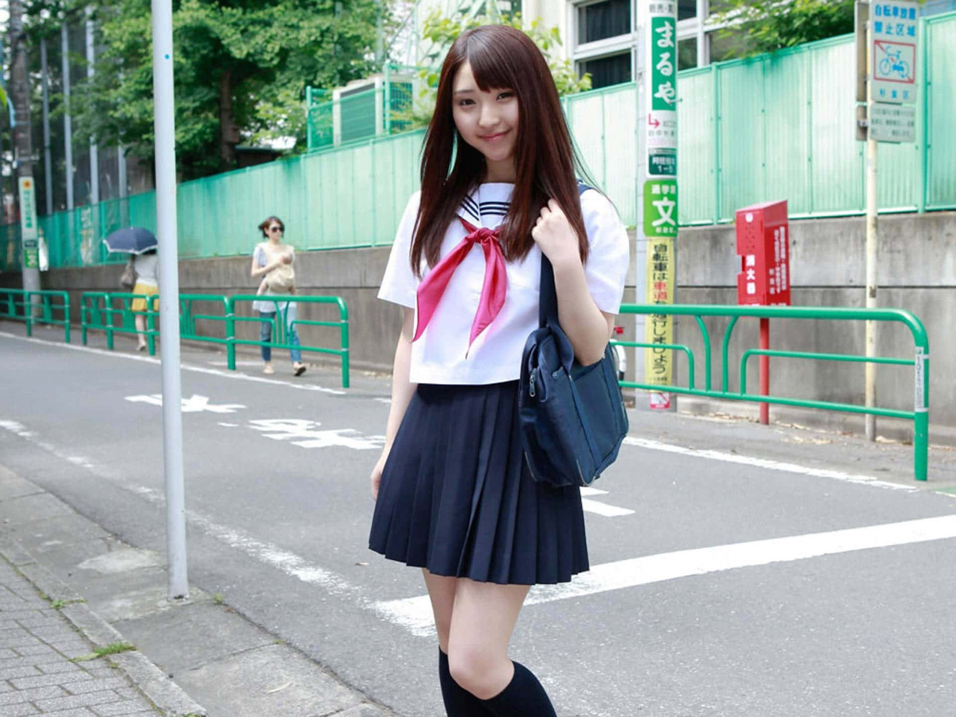 日本女學生身穿水手服在城市人行道上微笑