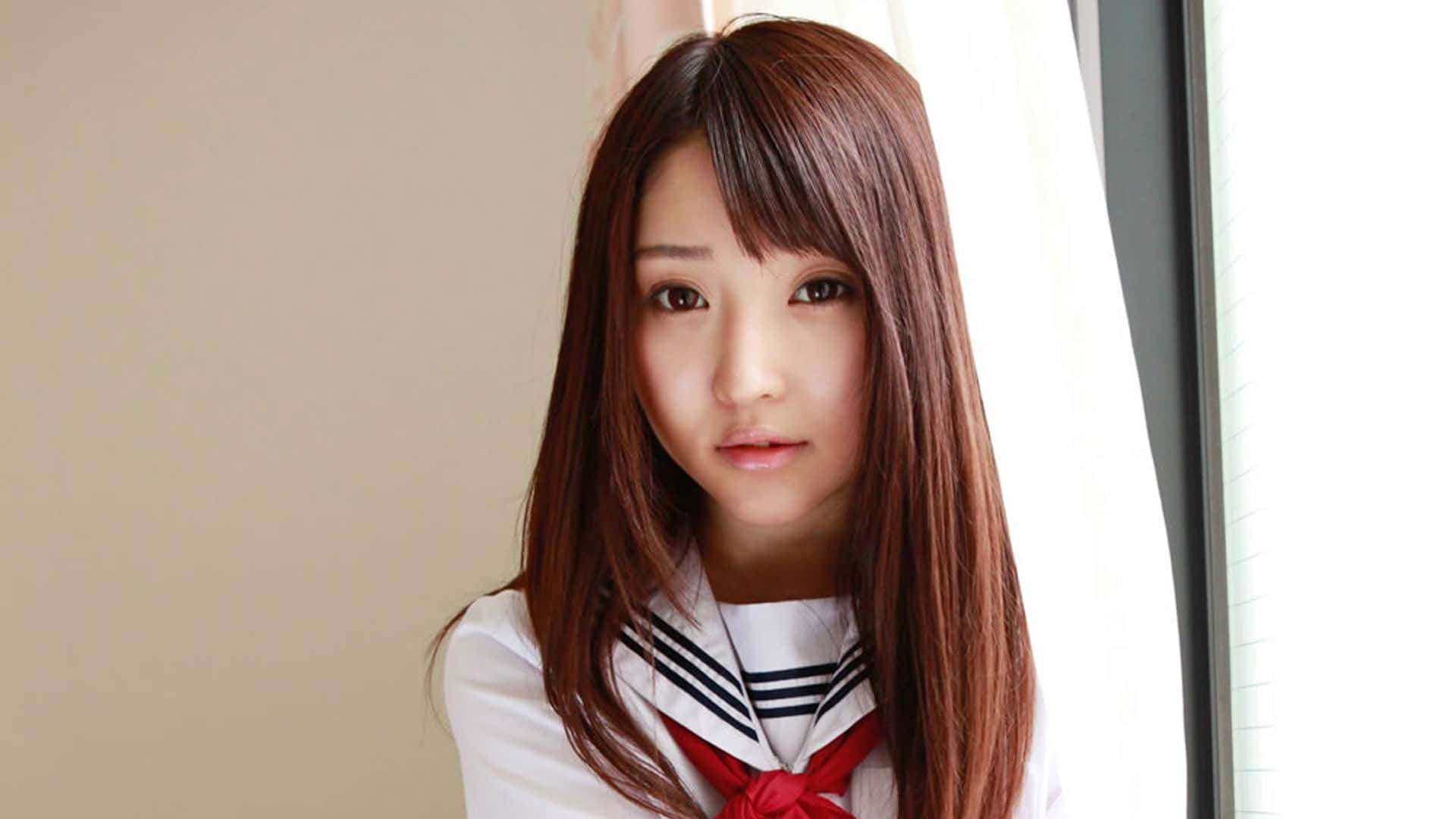 年輕女性穿著水手服站在窗邊