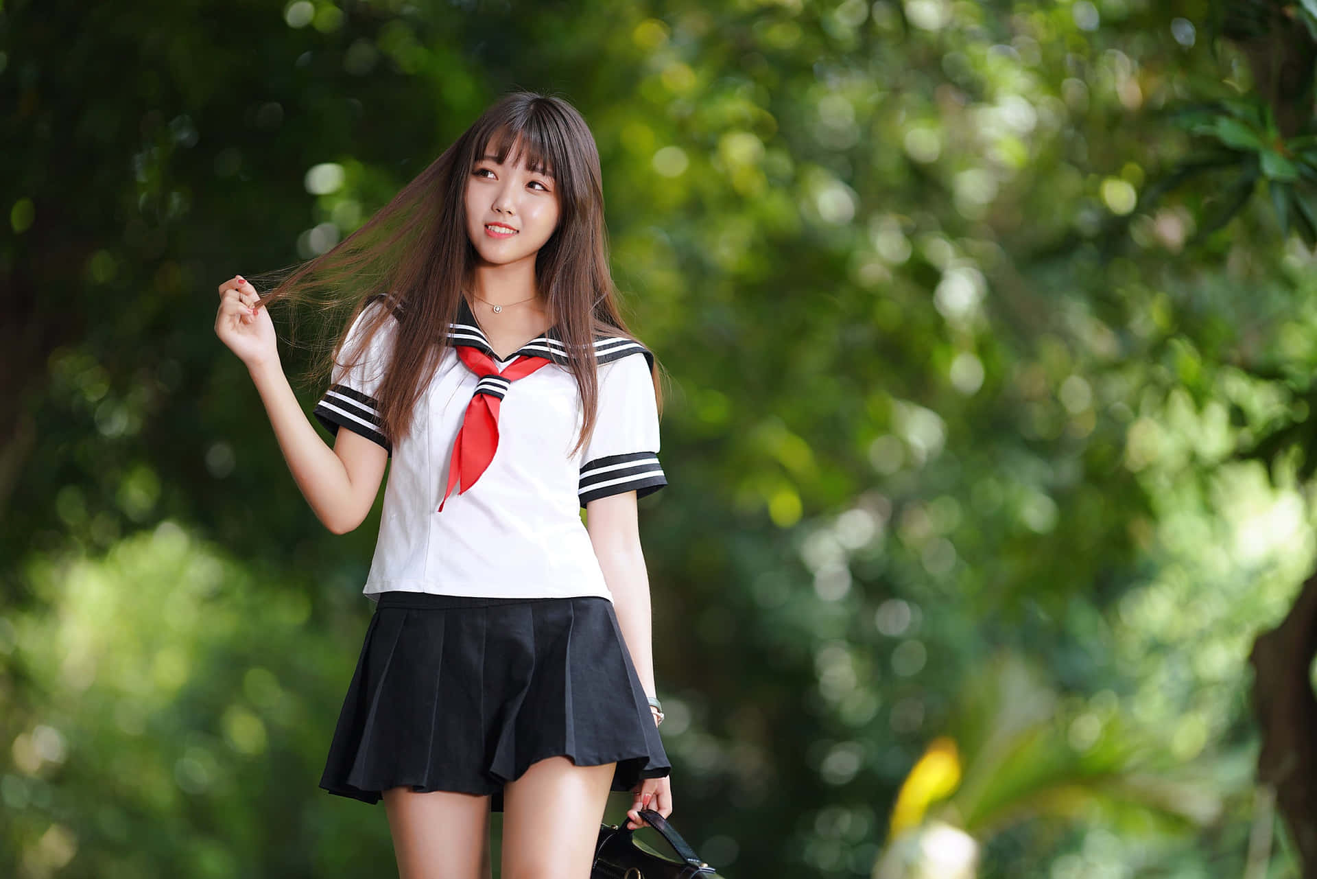 一個穿著校服的快樂女孩站在綠色的戶外環境中。