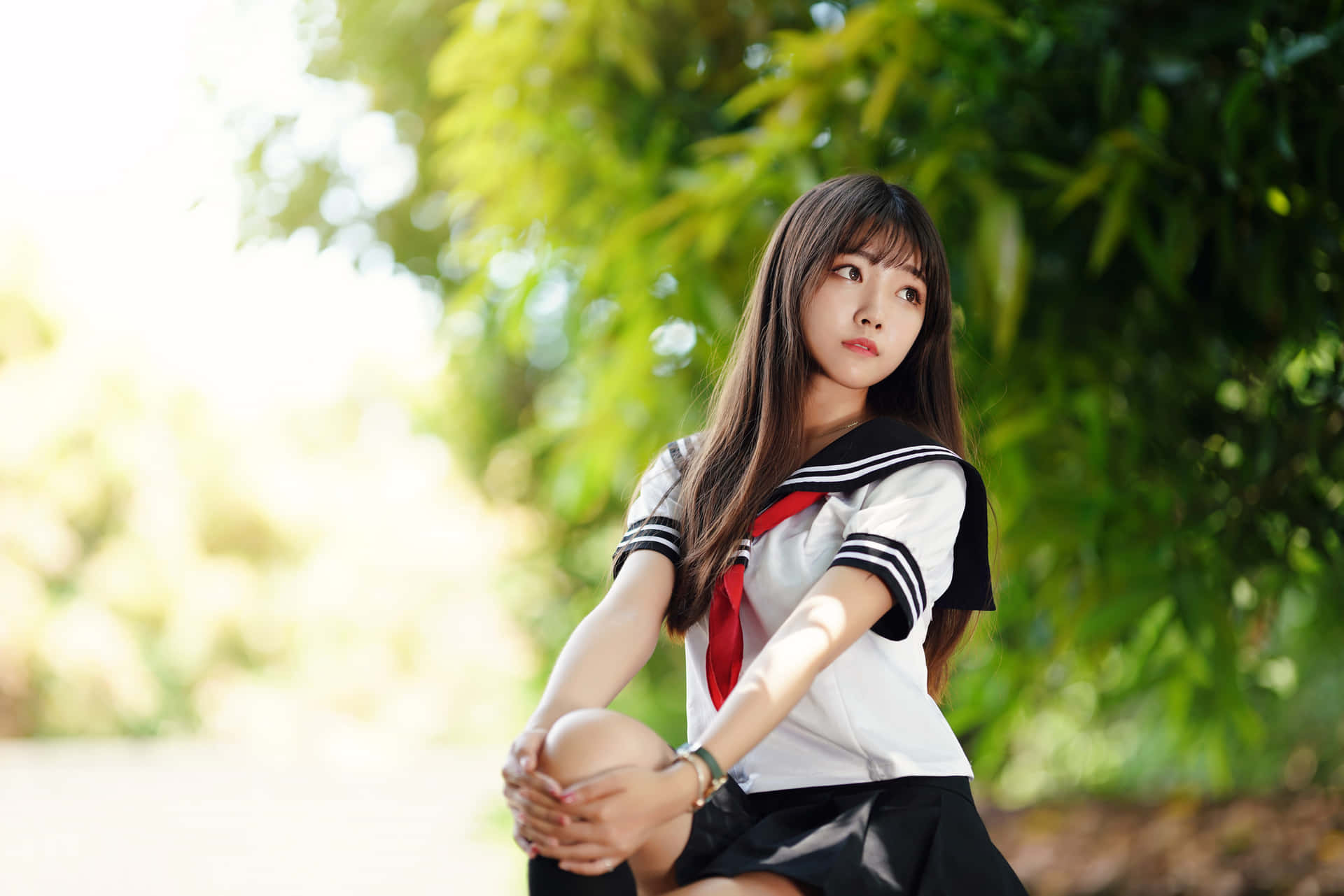 一位穿著水手服的年輕女性坐在陽光普照的花園戶外。