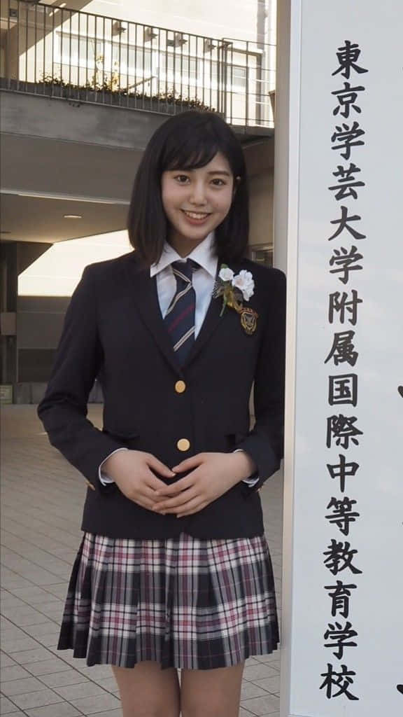 身穿校服的日本女學生在標牌旁微笑