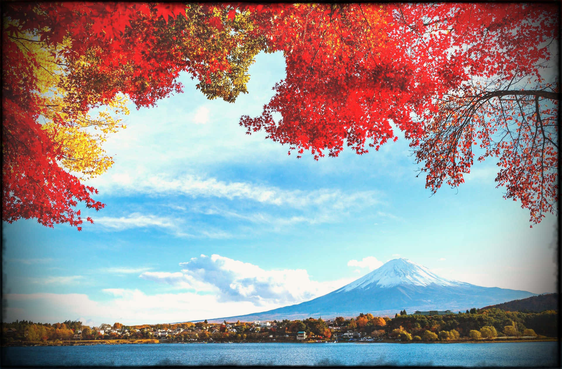 白雪覆蓋的富士山被平靜湖面上的紅色秋葉環繞。