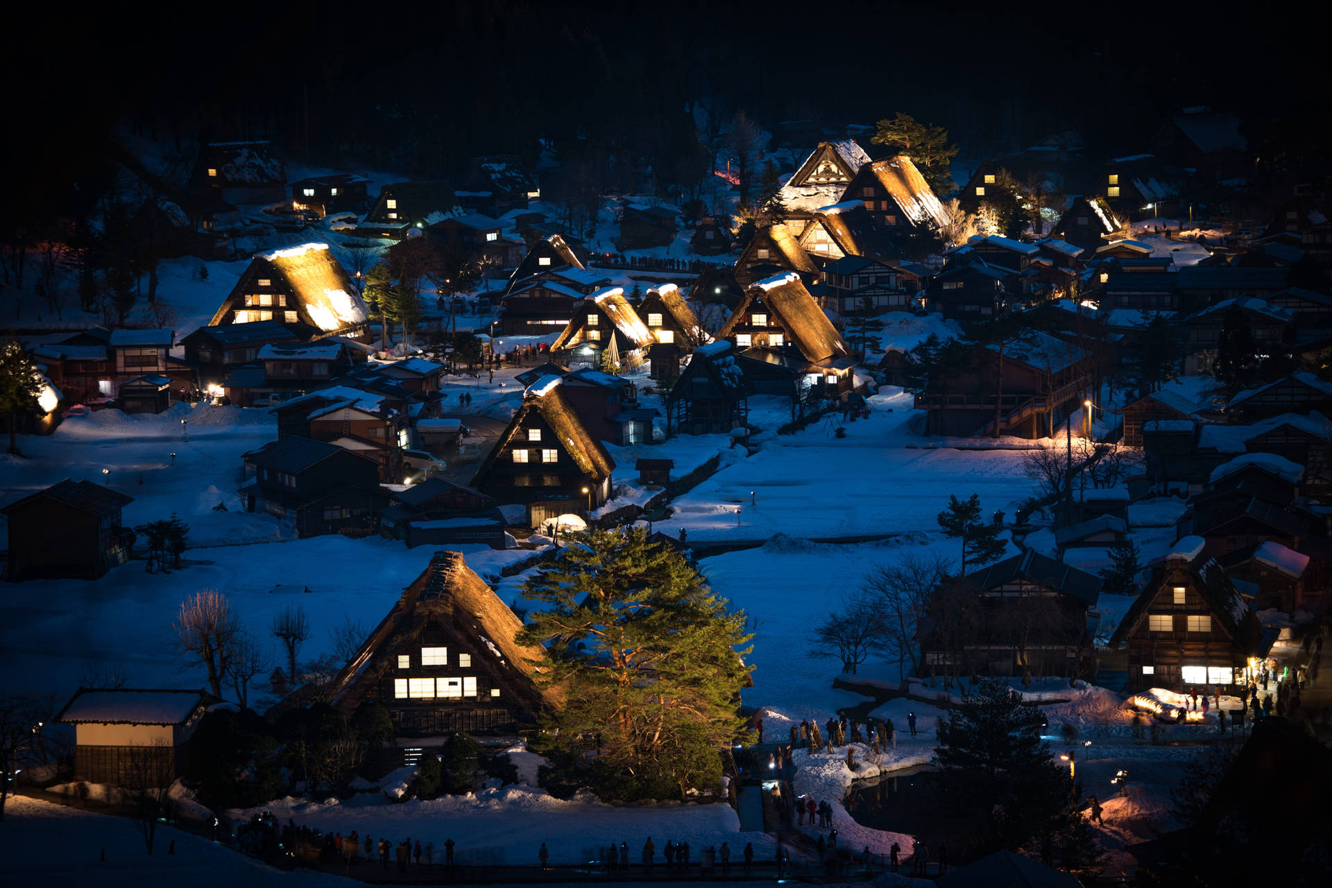 白雪覆蓋的茅草屋頂村莊在夜晚溫暖地發光。