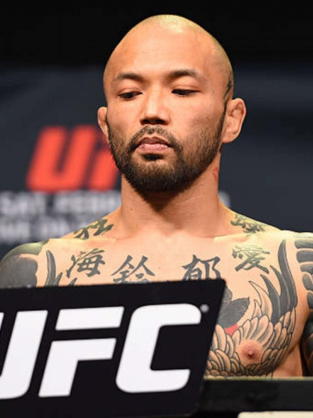 日本綜合格鬥選手山本信一郎中景照 壁紙 — 一位剃光頭、留鬍子、有紋身的UFC拳手莊嚴地站在稱重台上。