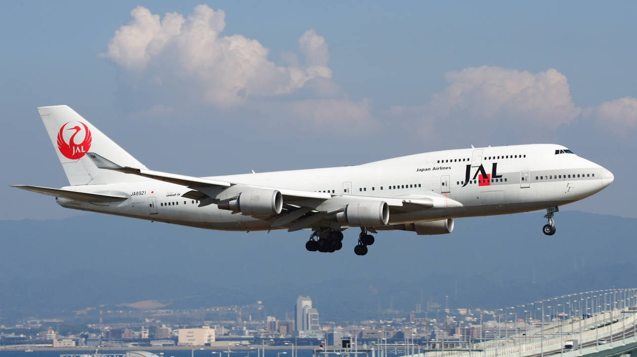 日本航空波音747降落，城市在背景中