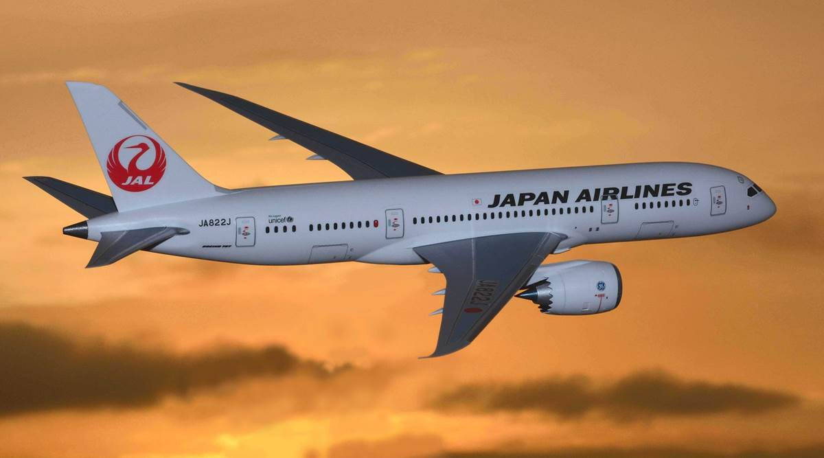 日本航空飛機在日落時分飛行，天空呈橙色並伴有雲朵