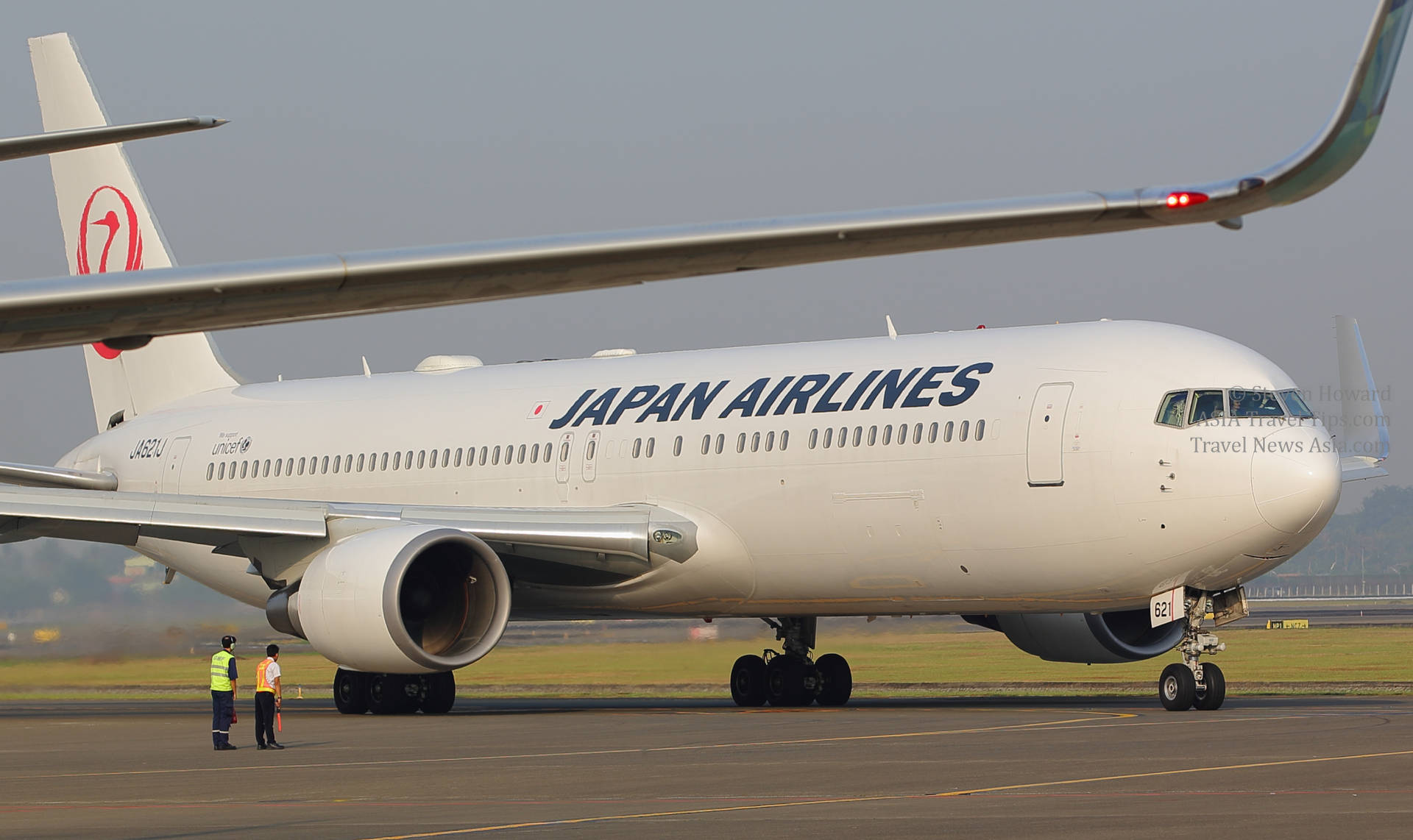 日本航空飛機在跑道上，地勤人員在附近