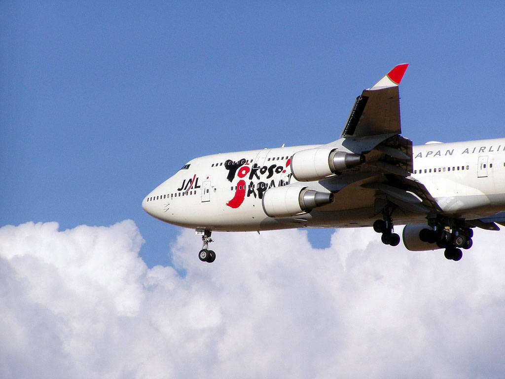 日本航空波音747放下起落架穿過雲層下降。