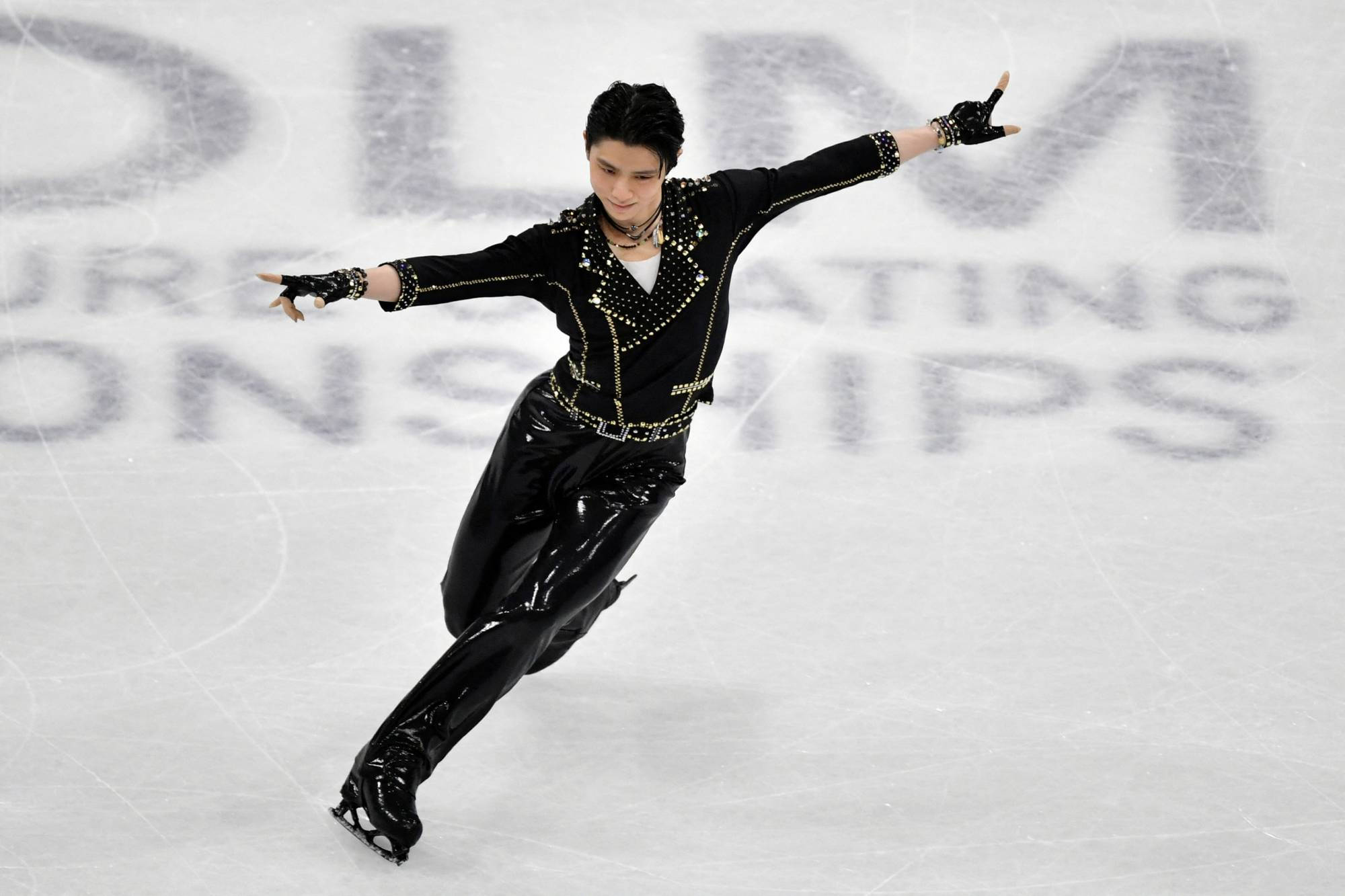 日本花式滑冰巨星羽生結弦世界花式滑冰錦標賽 壁紙 — 一名身穿黑色閃片服裝的男花樣滑冰選手在比賽中優雅地滑過冰場。
