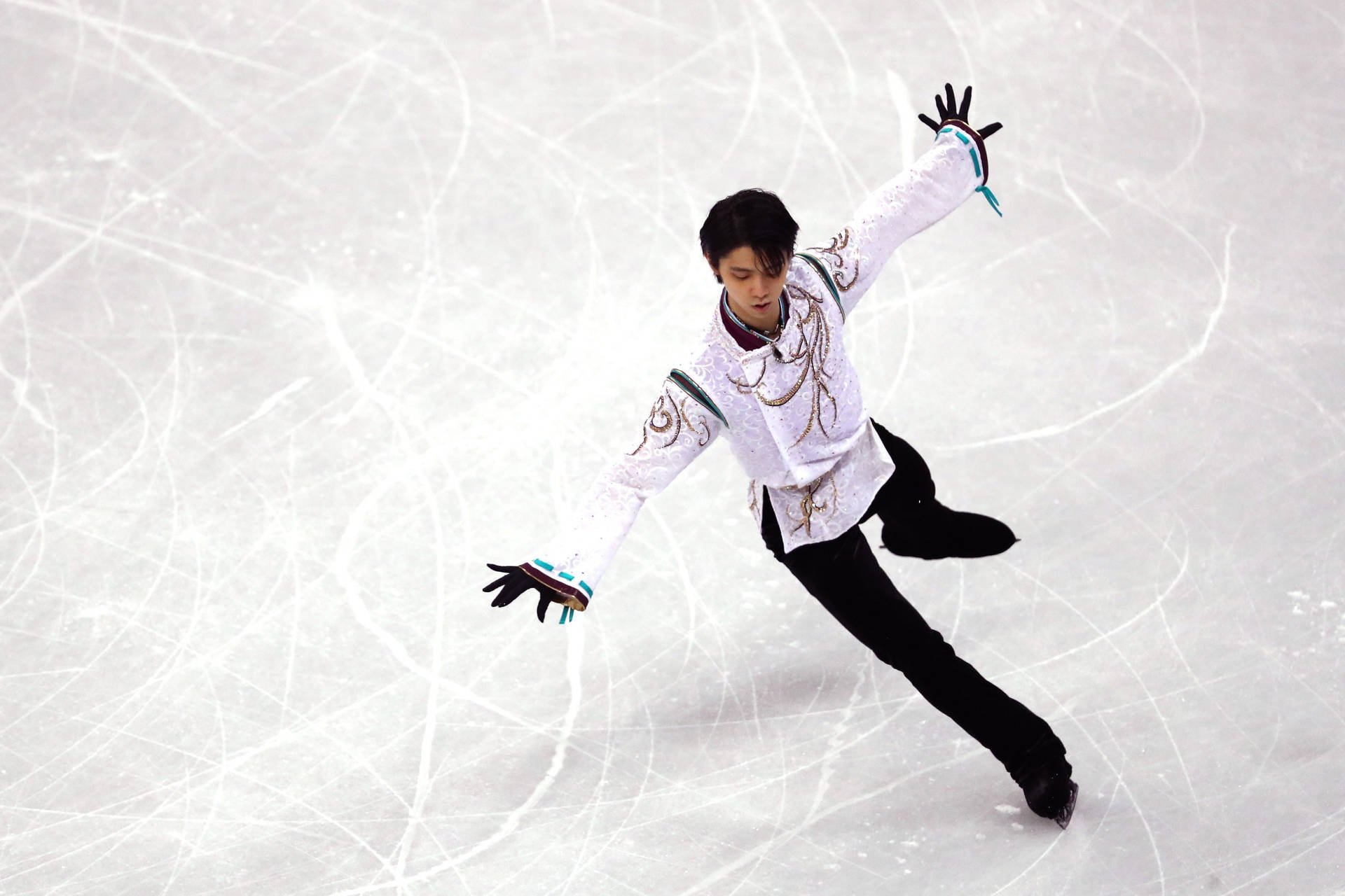 日本花式滑冰獎牌得主羽生結弦於平昌奧運會 壁紙 — 一名身穿白色刺繡服裝的男性花樣滑冰運動員，在佈滿劃痕的冰場上優雅地滑行，雙臂伸展。