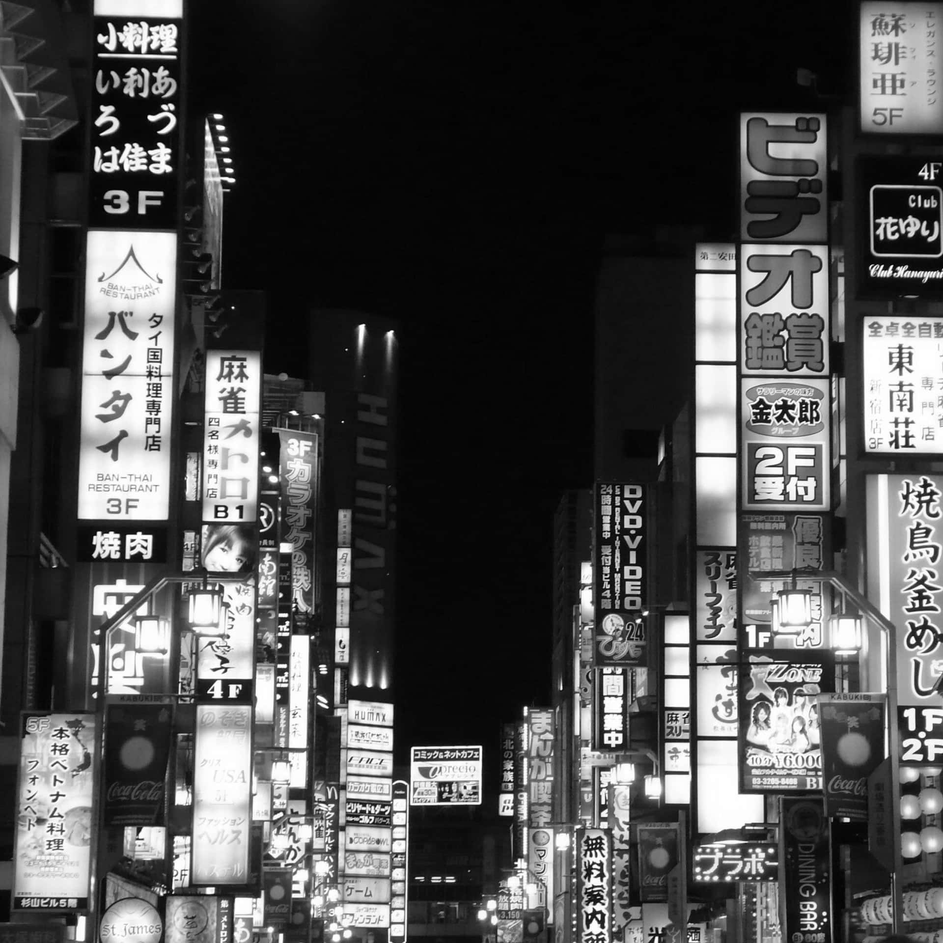 東京霓虹燈照亮城市街道的黑白照片，帶有日文標誌。