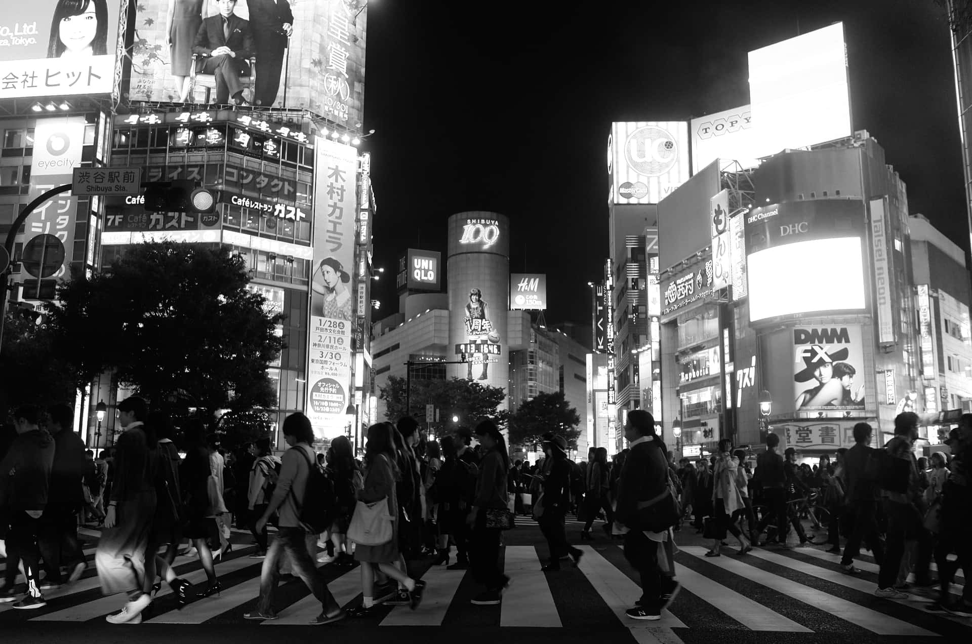 人群在夜晚繁忙的東京街道上，在明亮的霓虹燈牌下穿越。