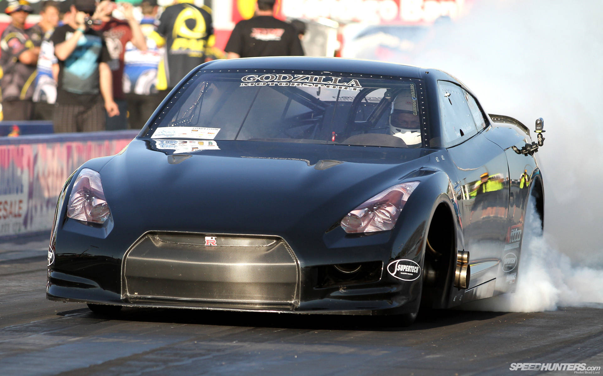 黑色日產GT-R在賽車活動中飄移冒煙。