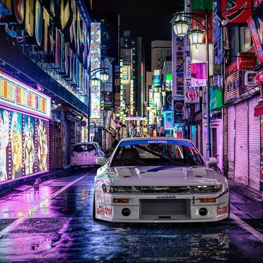 白色日產Skyline GT-R在夜晚東京濕漉漉的霓虹燈街道上