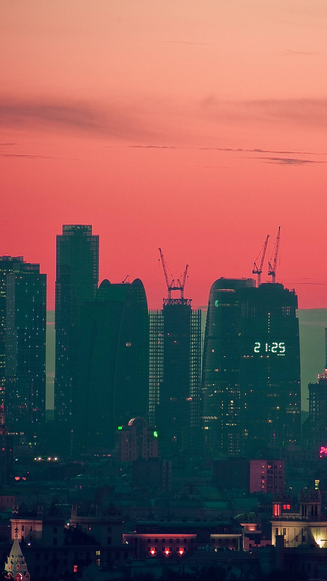 現代城市黃昏天際線，粉紅色和橙色天空，建築物燈光亮起。