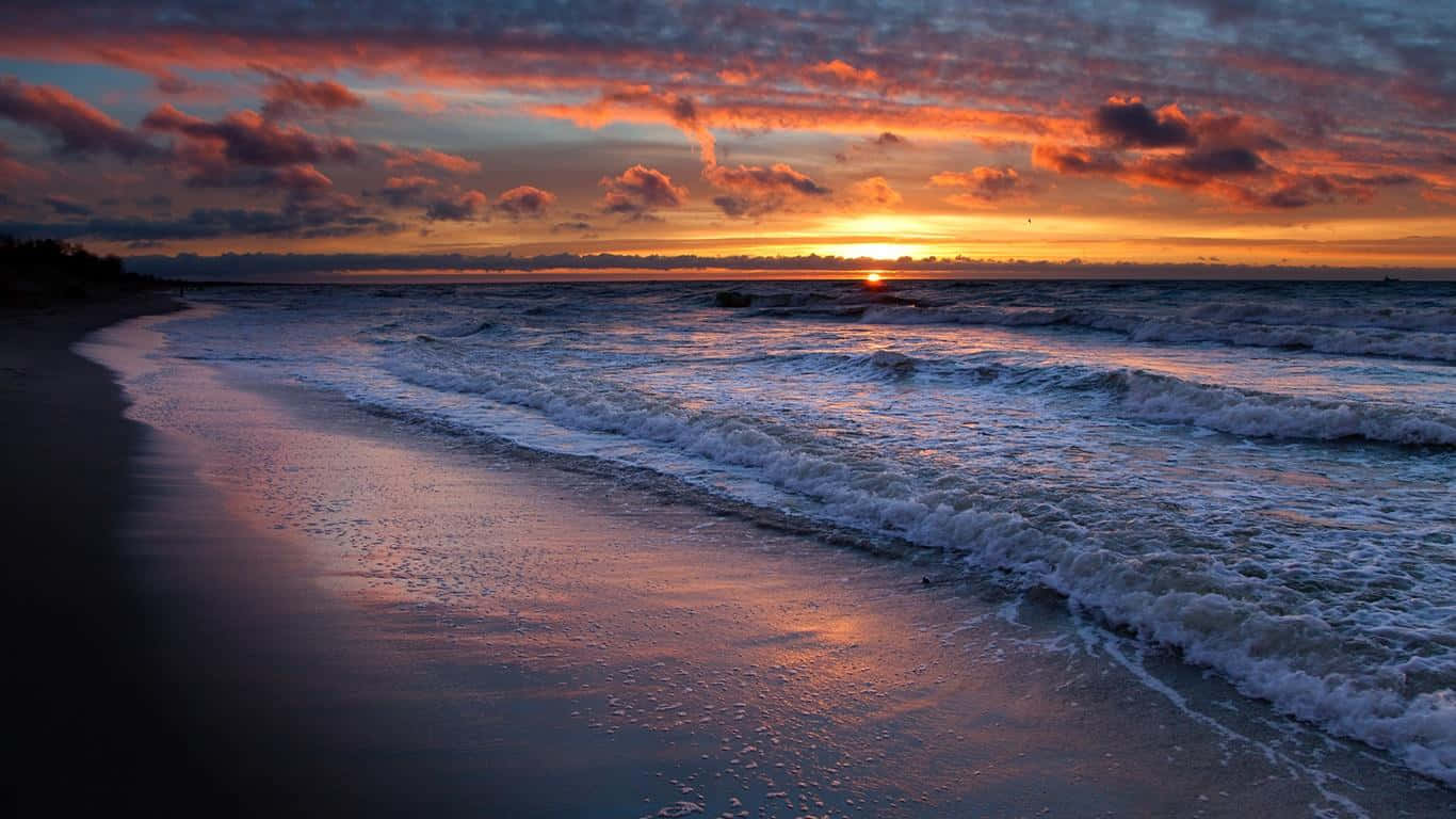 Sunset Landscape 桌布 壁紙 — 日落將天空染成火熱的橙色和粉紅色，海浪拍打著濕漉漉的沙灘。