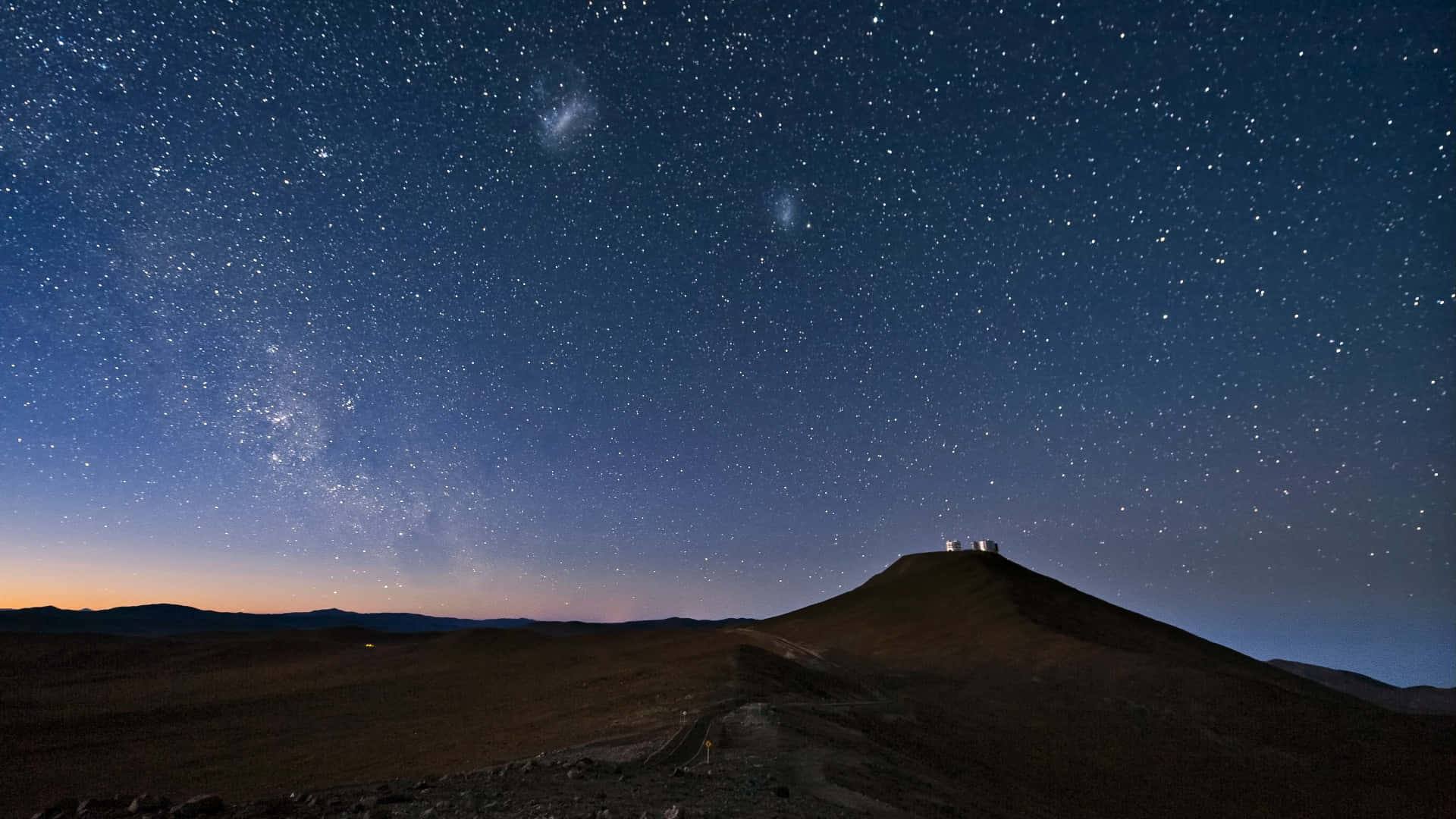 在銀河璀璨的星空下，沙漠山脊頂上的天文台圓頂。