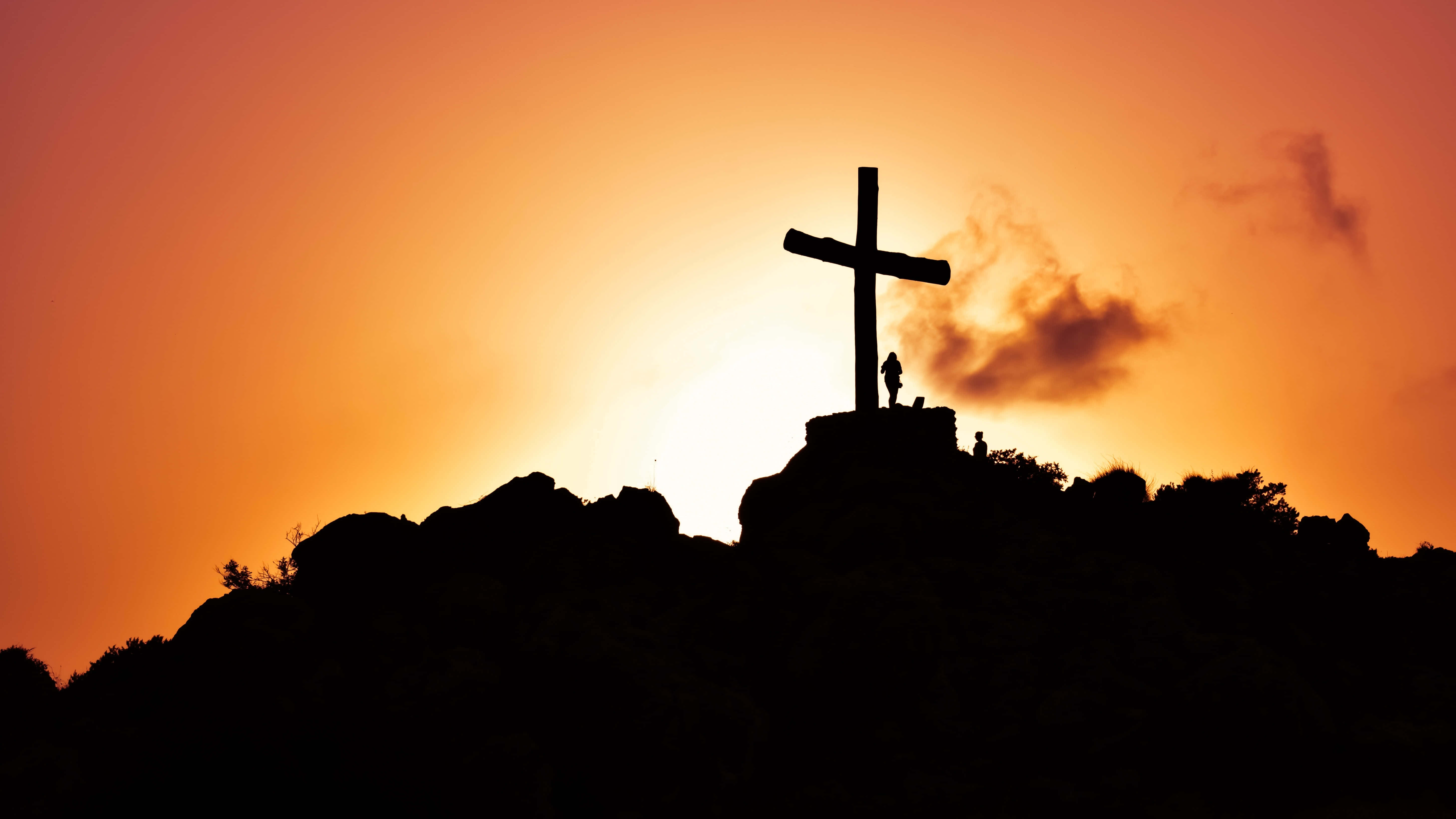 Jesus Resurrection 桌布 壁紙 — 日落時分，岩石山頂上十字架的剪影，兩個人影站在其陰影下。