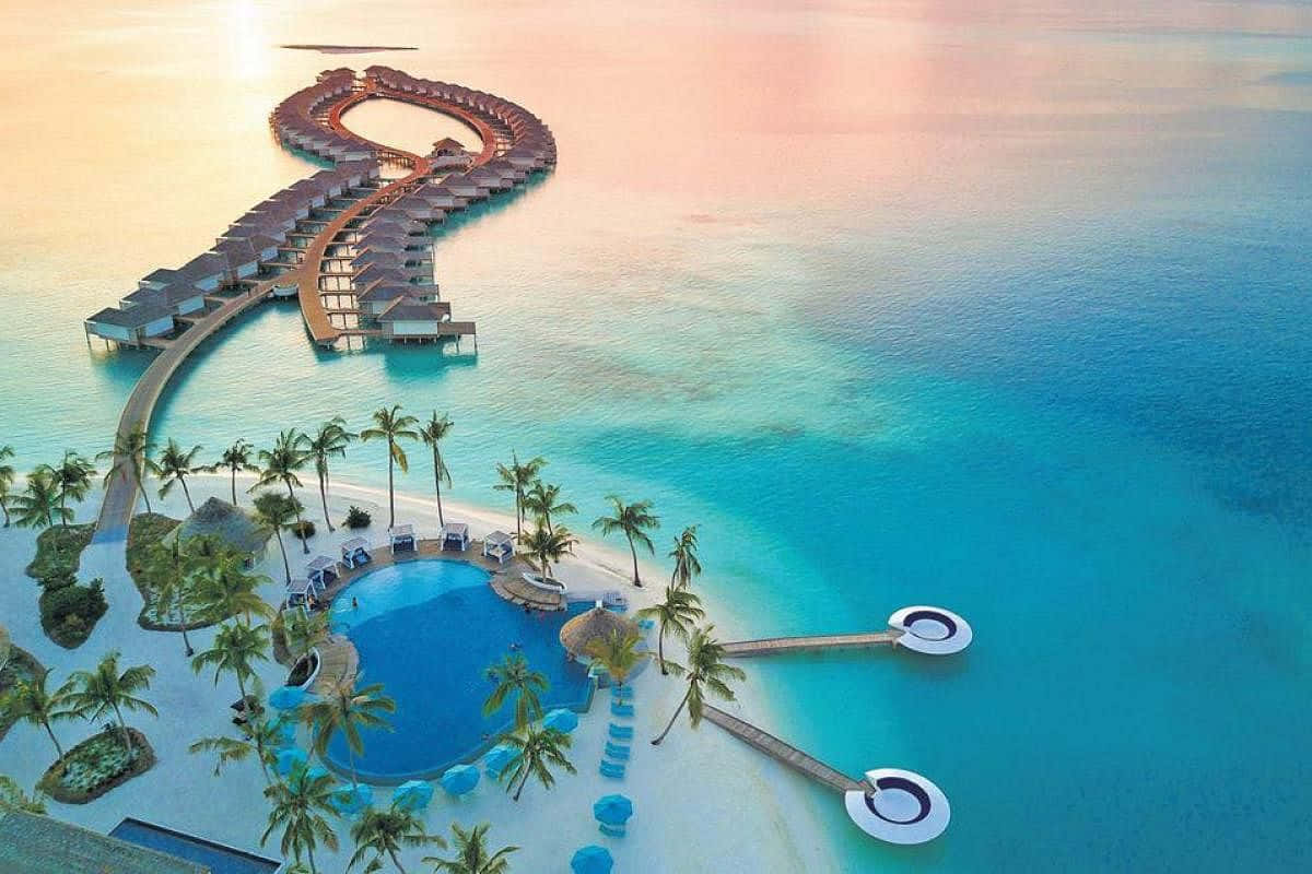 Maldives Island 桌布 壁紙 — 日落時分，豪華水上平房度假村蜿蜒穿過碧綠海水的鳥瞰圖。